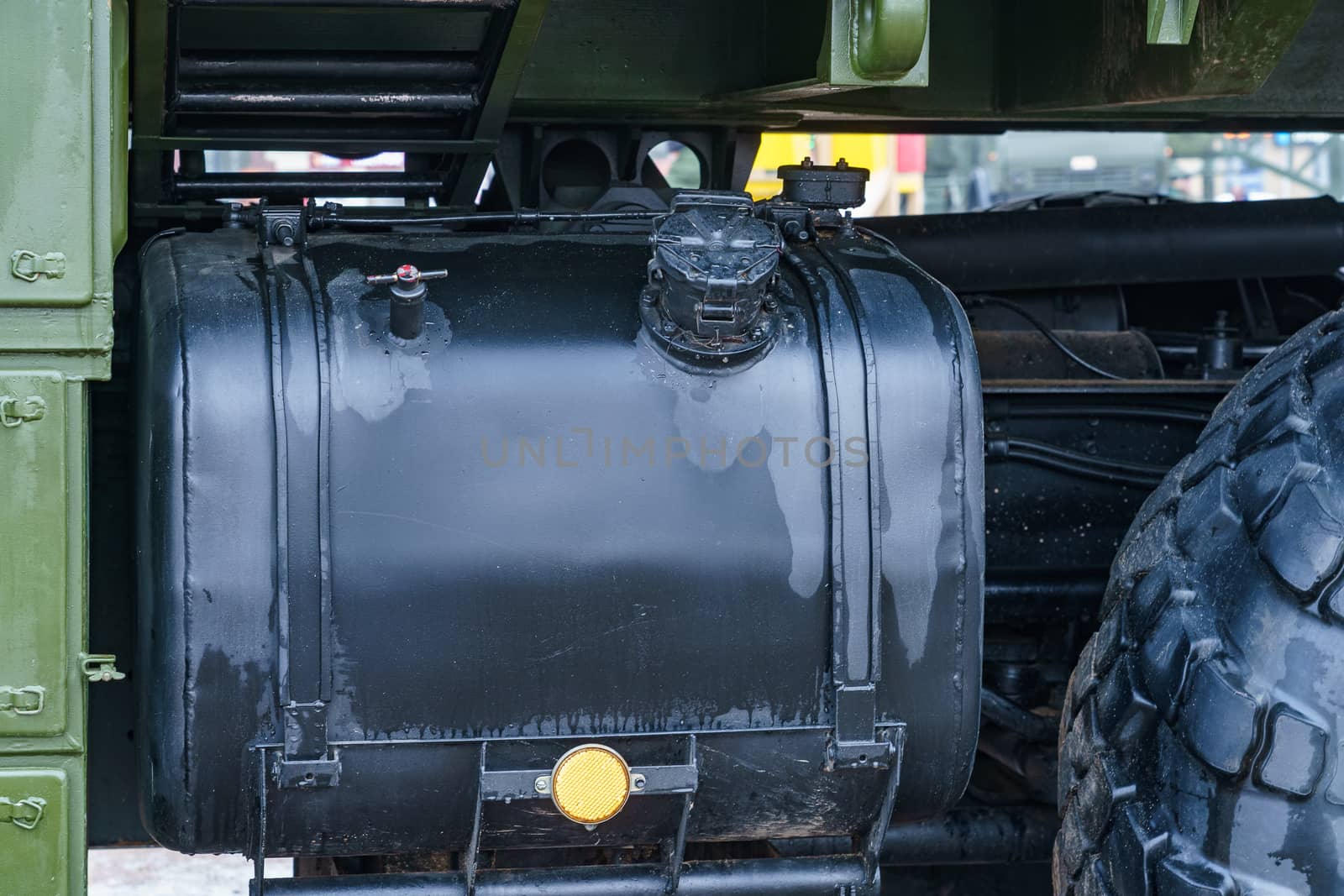 black tank of a military truck and part of a wheel