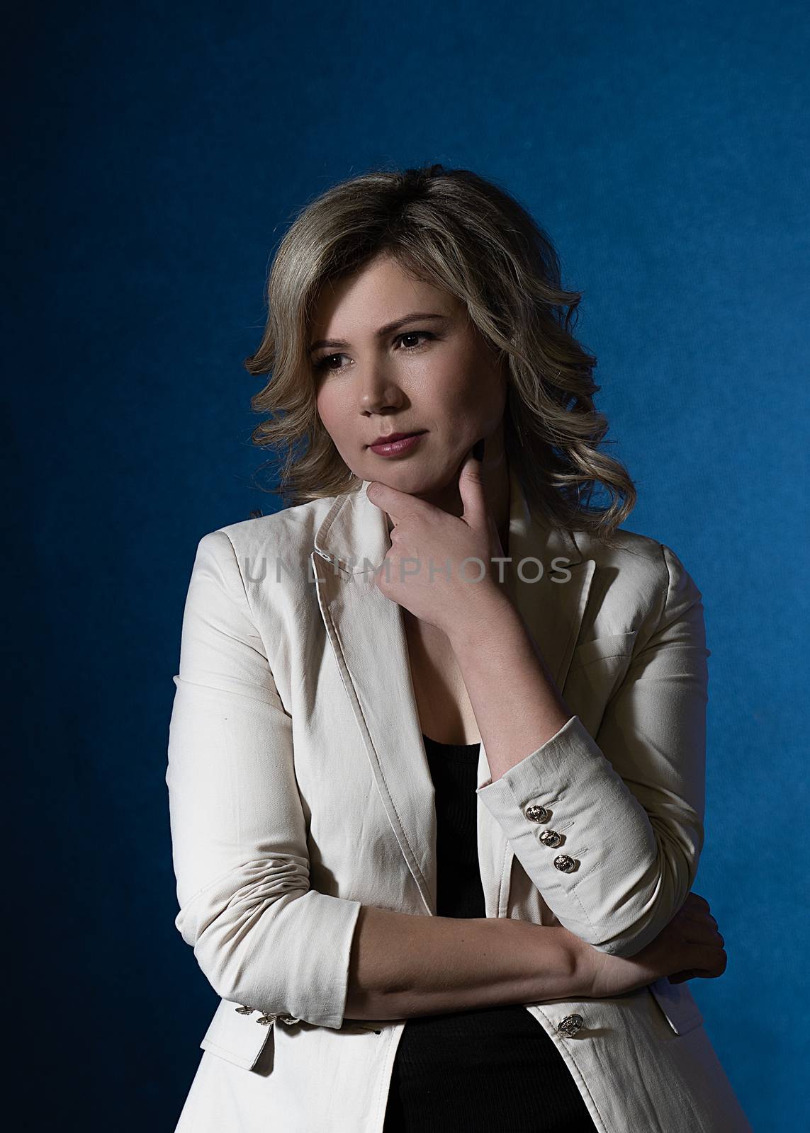 30 years old woman with blond hair in business clothes posing in the studio on a dark background