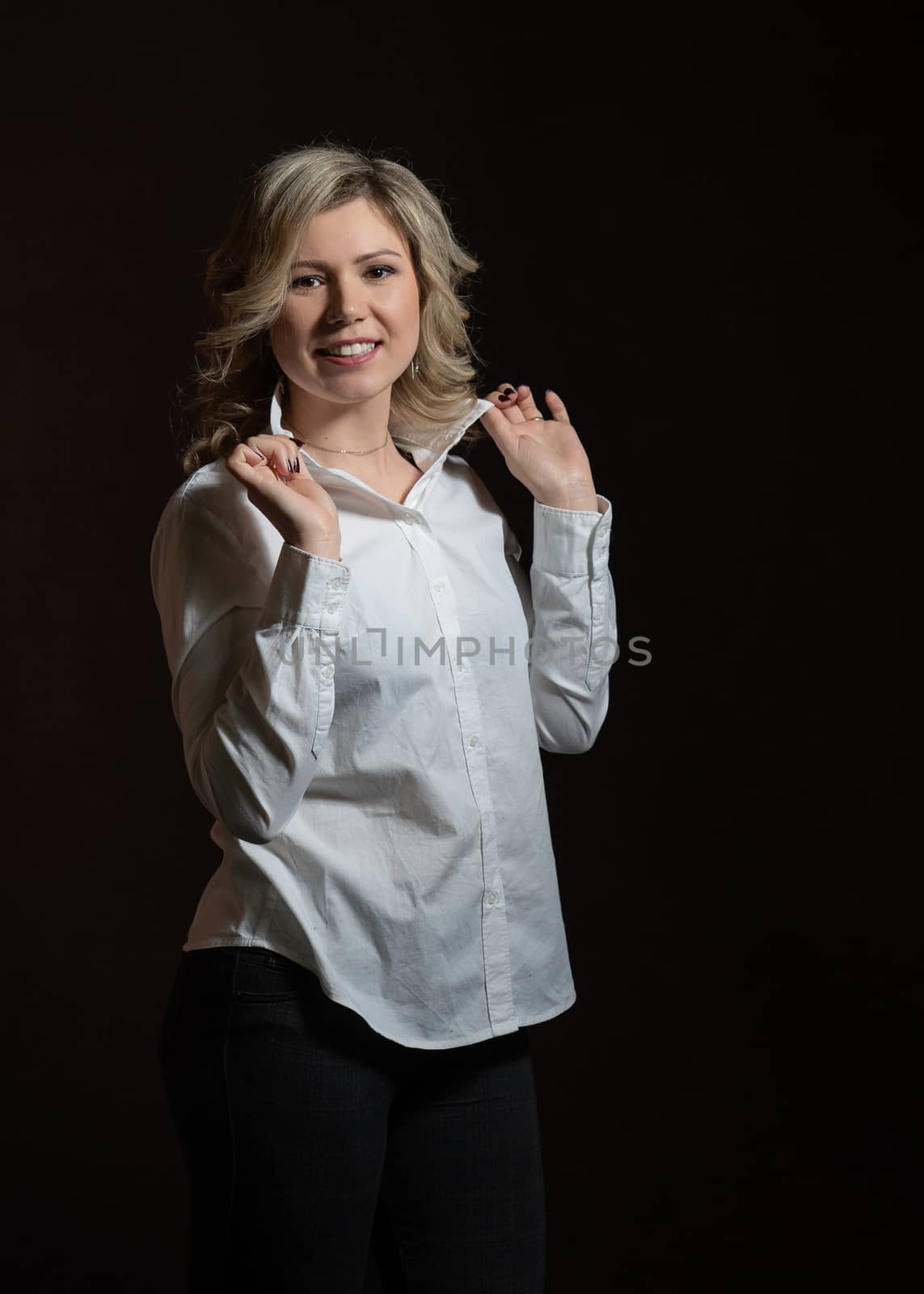 30 years old woman with blond hair in a white shirt posing in the studio on a dark background