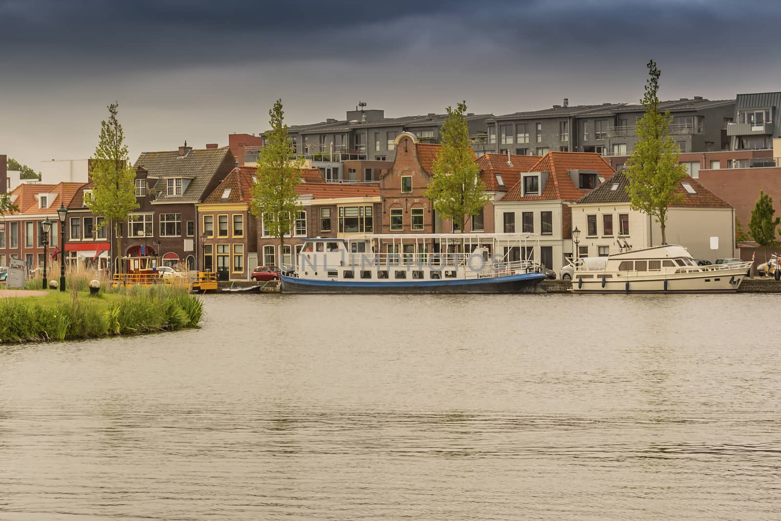 moored boats and old houses in front and new construction back in Alkmaar. netherlands holland