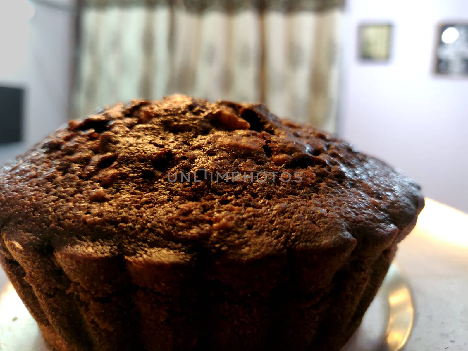 A close up of chocolate walnut muffin on a steel plate held up in the air