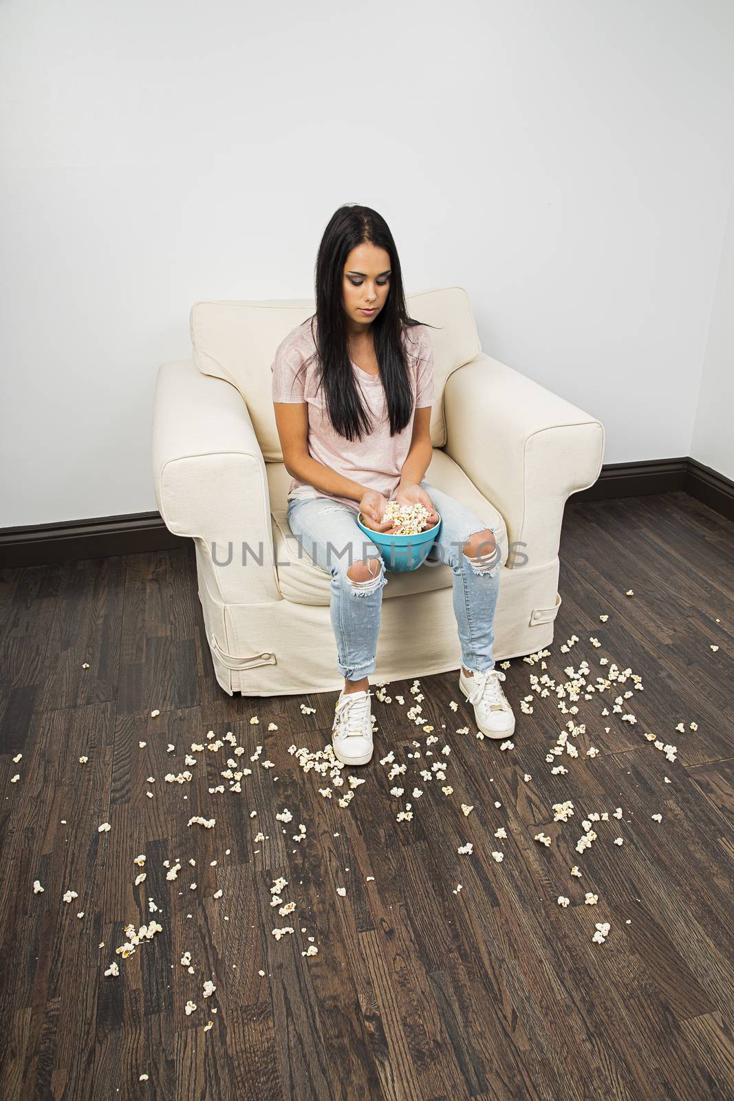 young woman with two hands in a bowl of popcorn making a mess