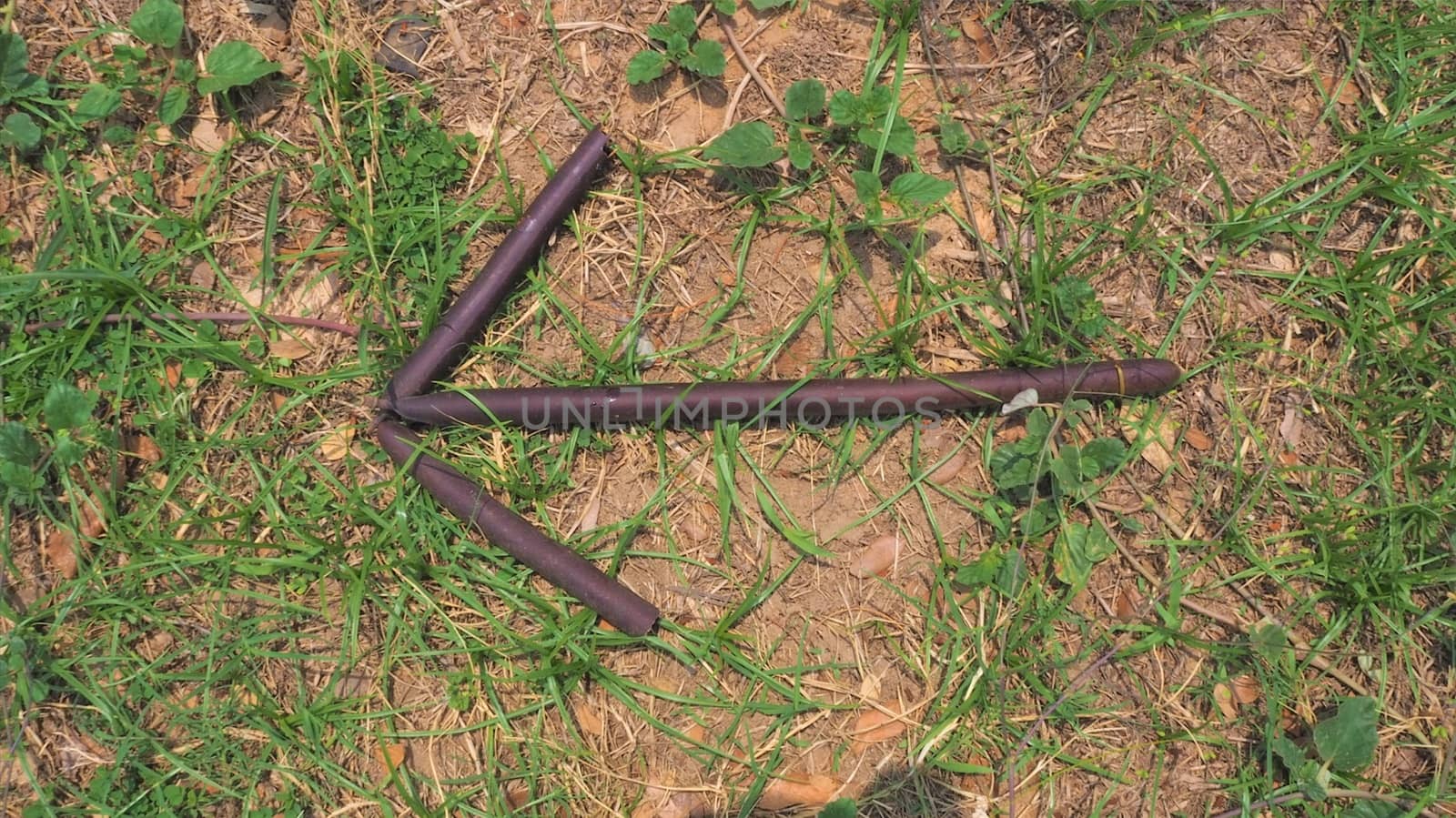 bush craft bushcraft stick arrow pointing left on grass and brown wooden sticks survival military sign signal