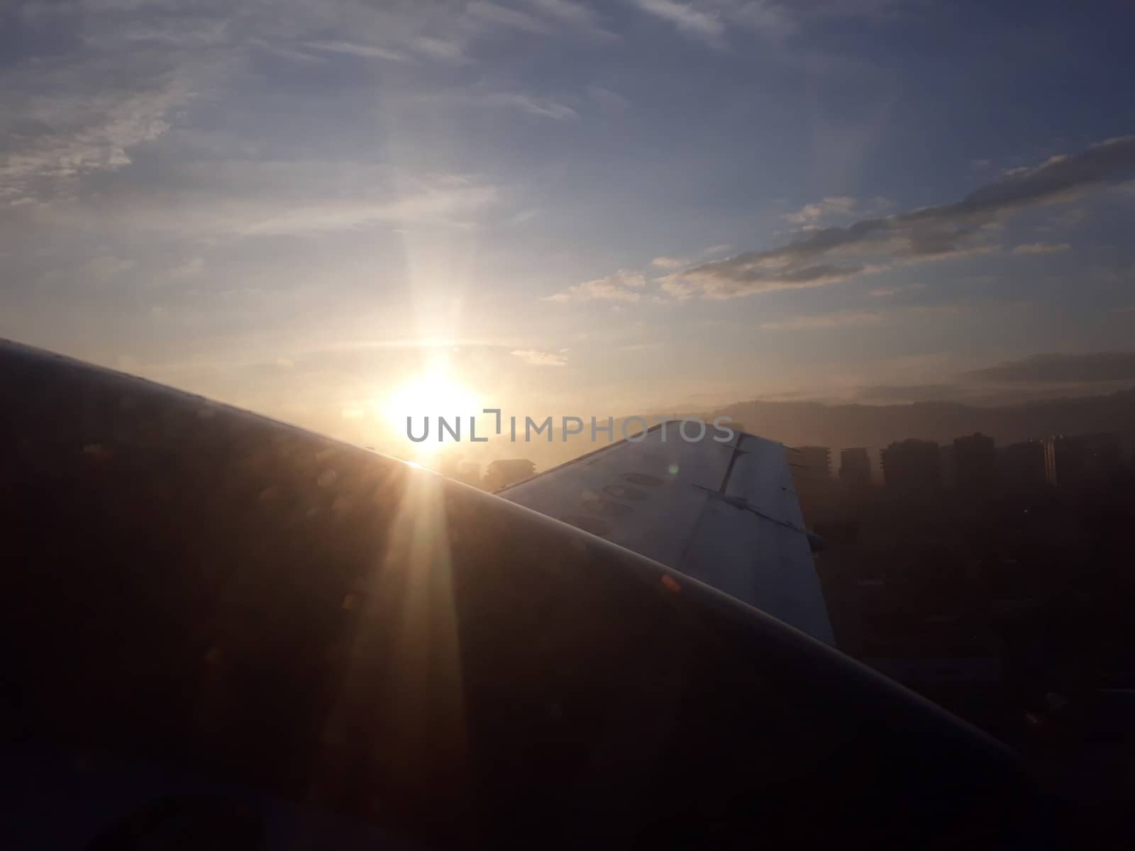 flying with the sun rising setting over the airplane wing