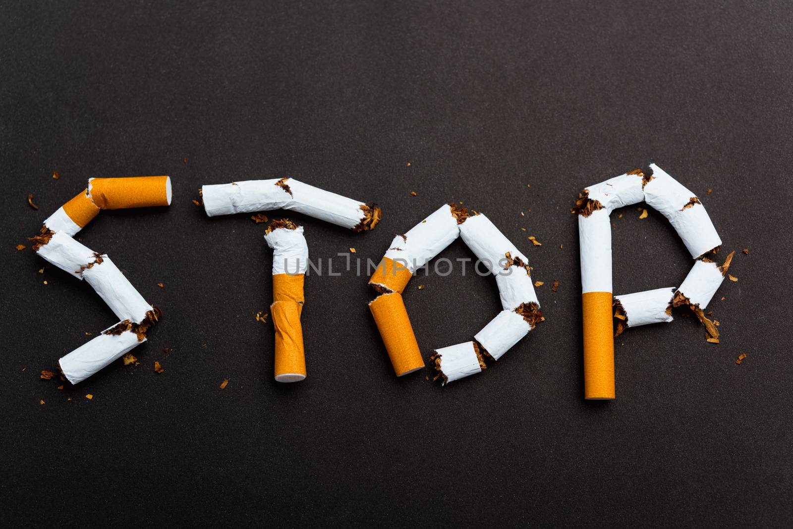 31 May of World No Tobacco Day, no smoking close up word STOP spelled text of the pile cigarette or tobacco on black background with copy space, and Warning lung health concept