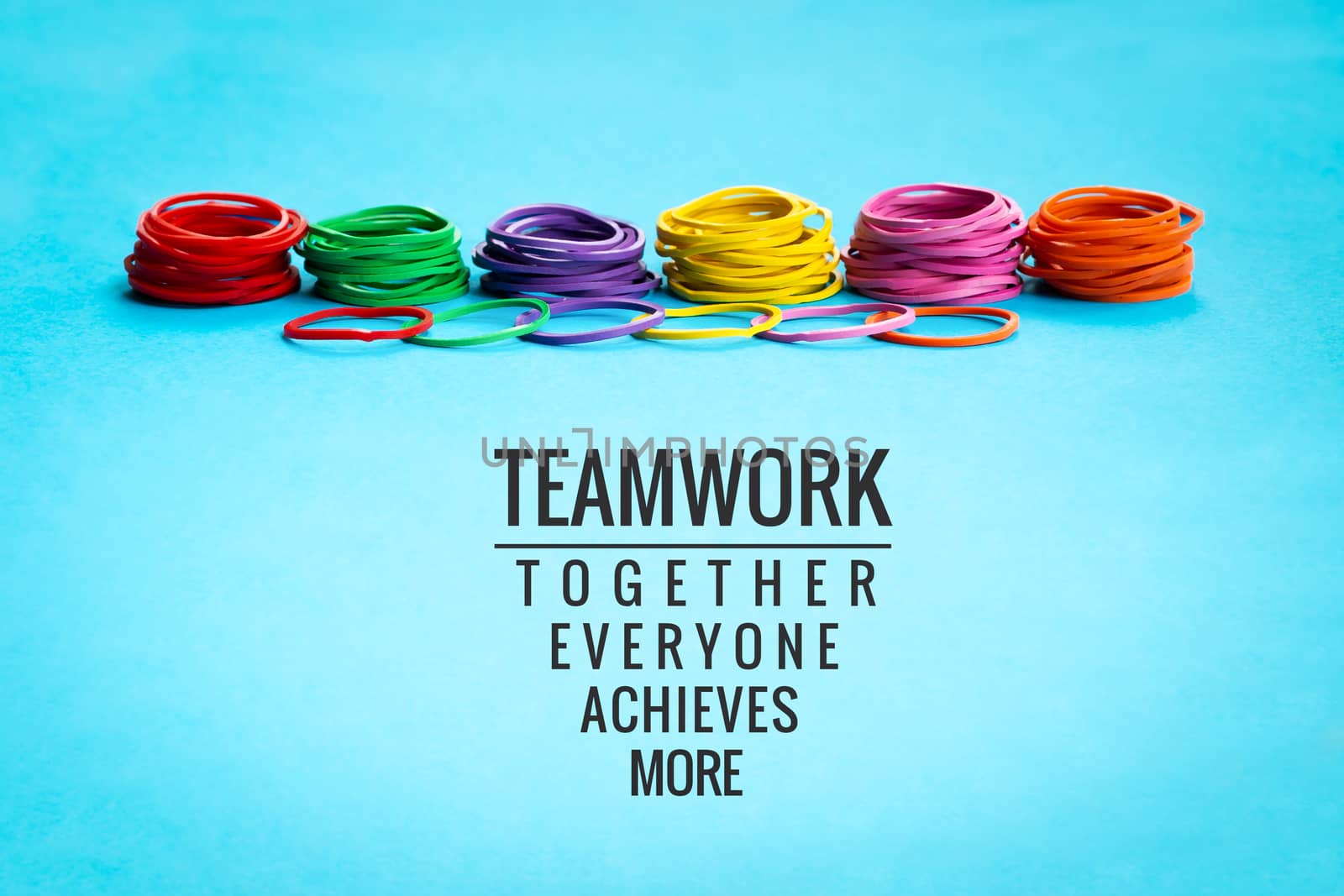Teamwork concept. group of colorful rubber band on blue background with word Teamwork, Together, Everyone, Achieves and More