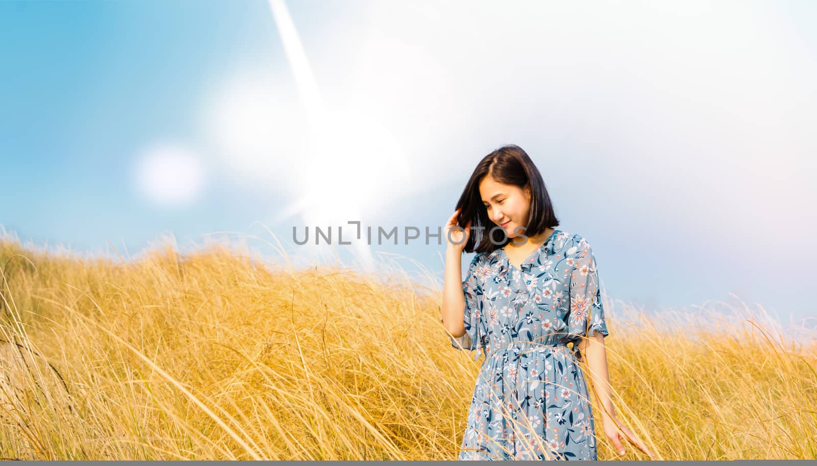 Asia Girl Outdoors enjoying nature. girl in blue dress walking on the Spring Field, Sun Light.