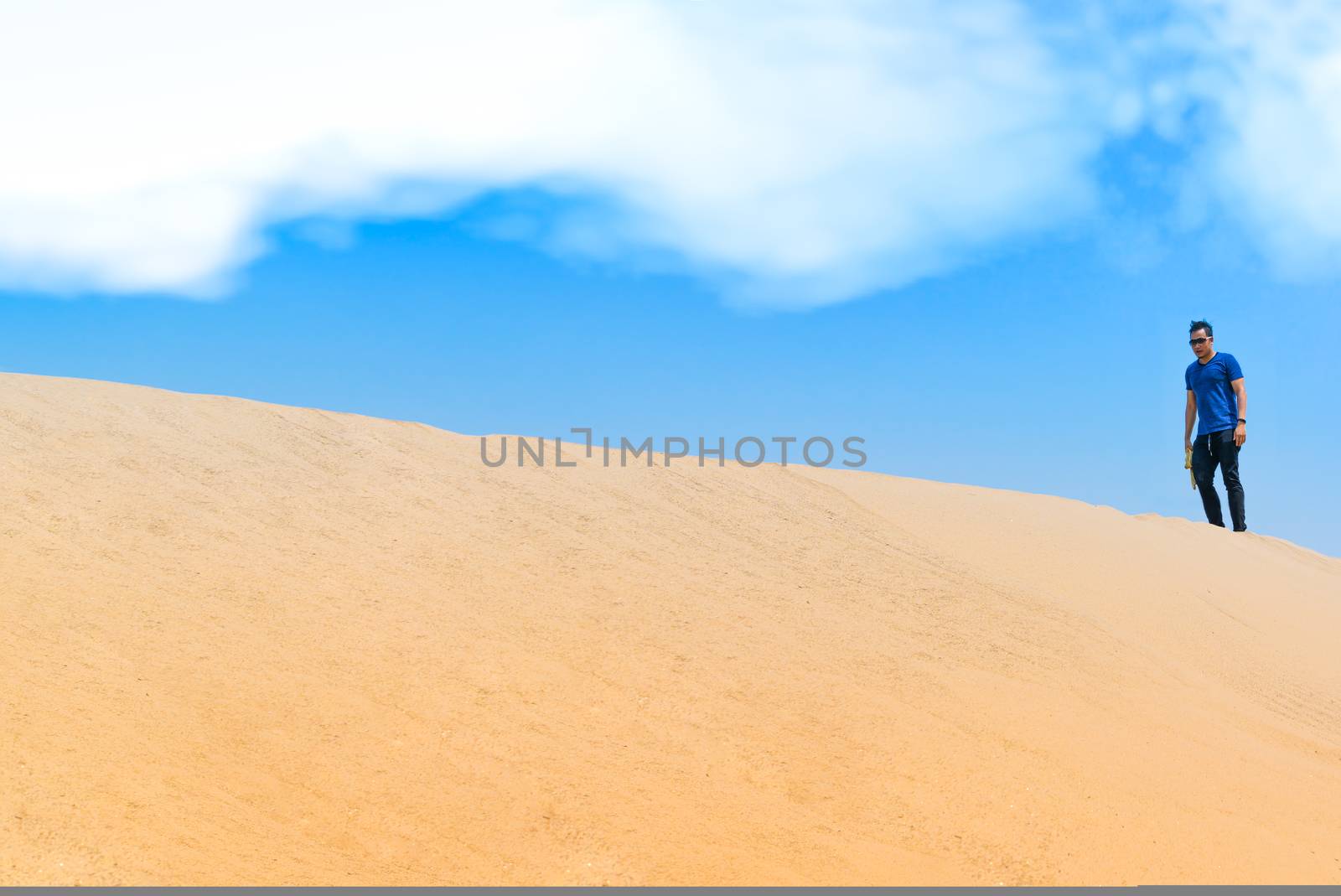 Young man in casual clothes walking forward in the desert