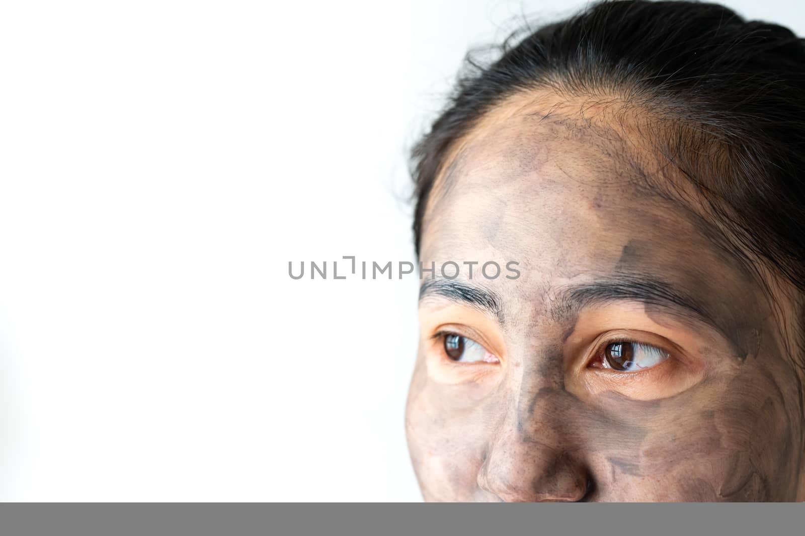 asia woman applied charcoal mask on her bare face