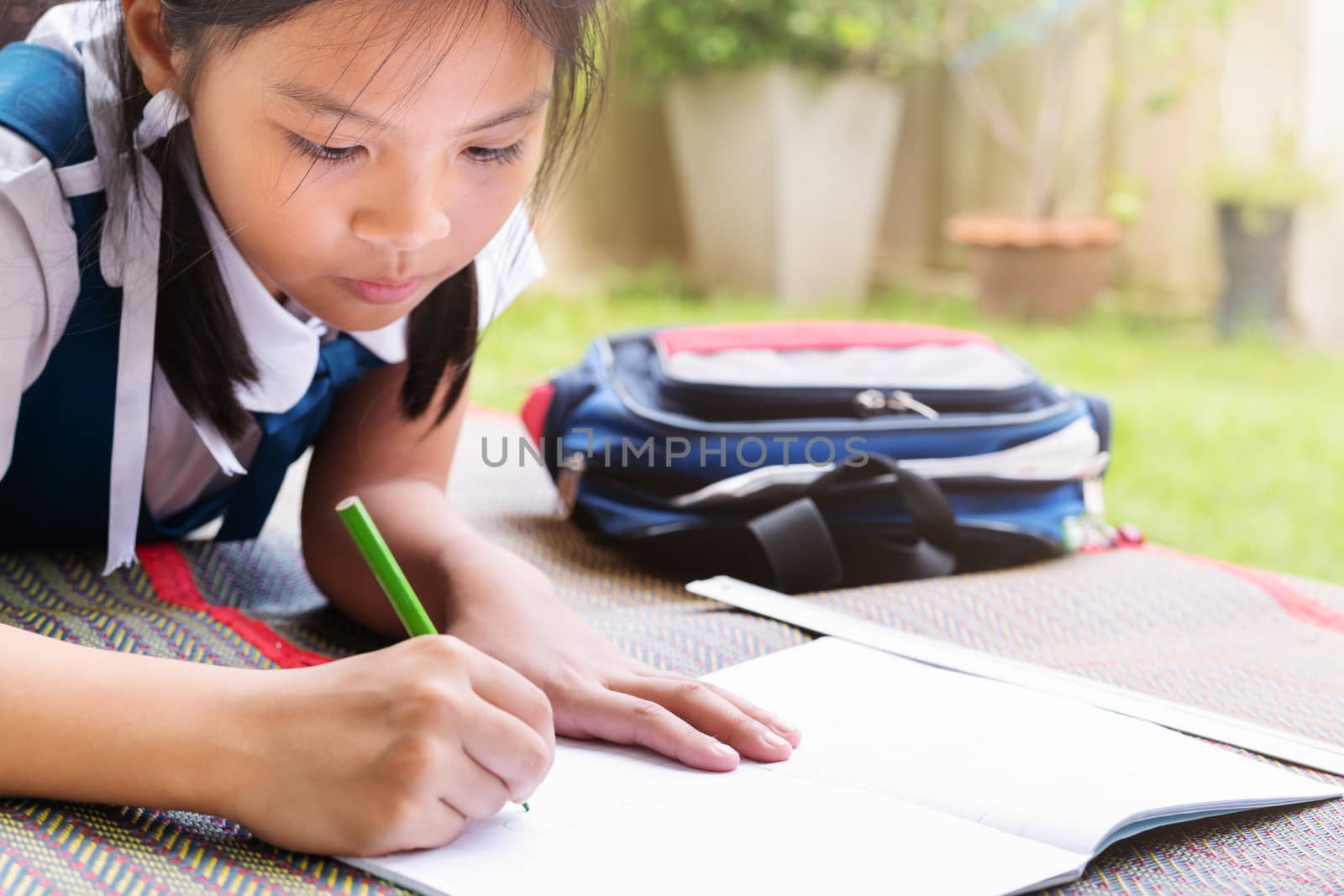 little girl writes to writing-books. The decision of lessons. girl lay down drawing the picture