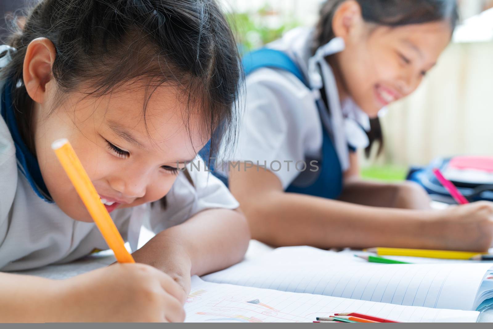 two sister girl writes to writing-books. The decision of lessons. girl lay down drawing the picture