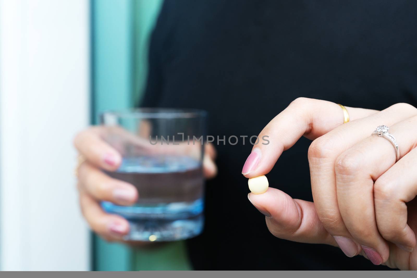 medicine, health care and people concept - close up a pill on woman hand