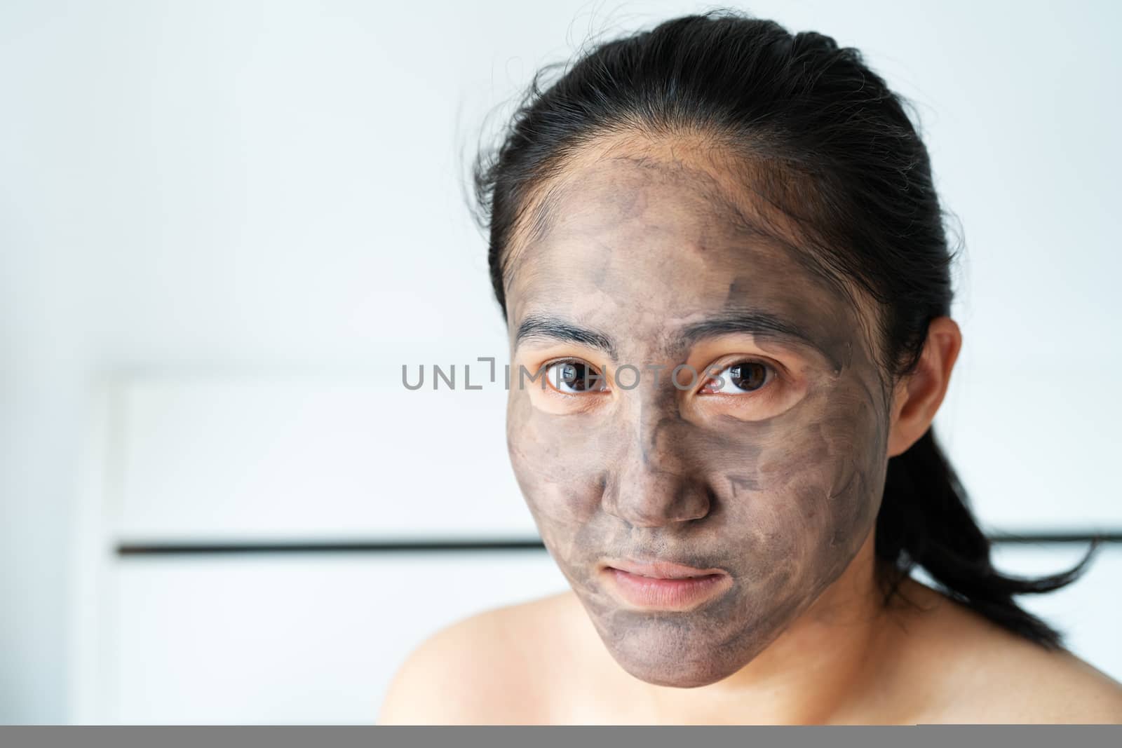 asia woman applied charcoal mask on her bare face