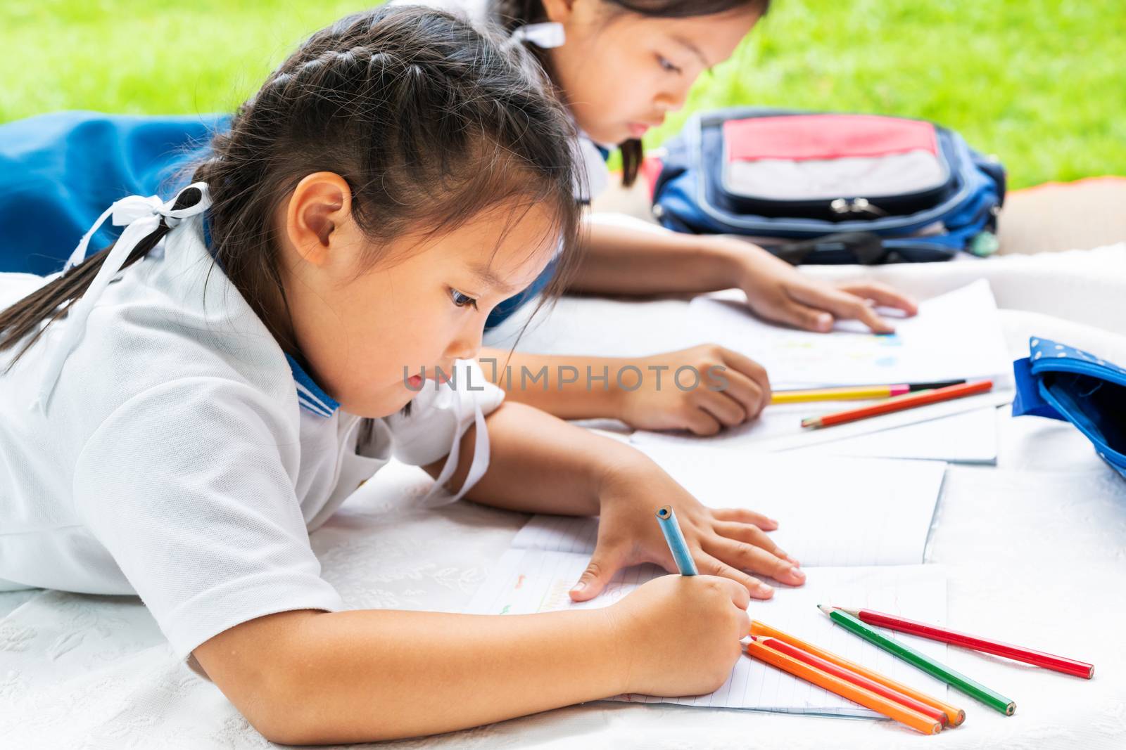 two sister girl writes to writing-books. The decision of lessons. girl lay down drawing the picture