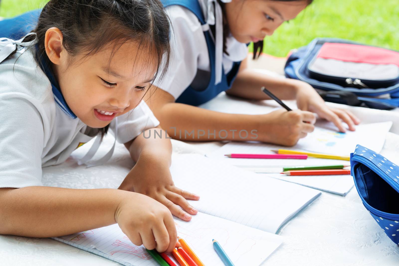two sister girl writes to writing-books. The decision of lessons. girl lay down drawing the picture