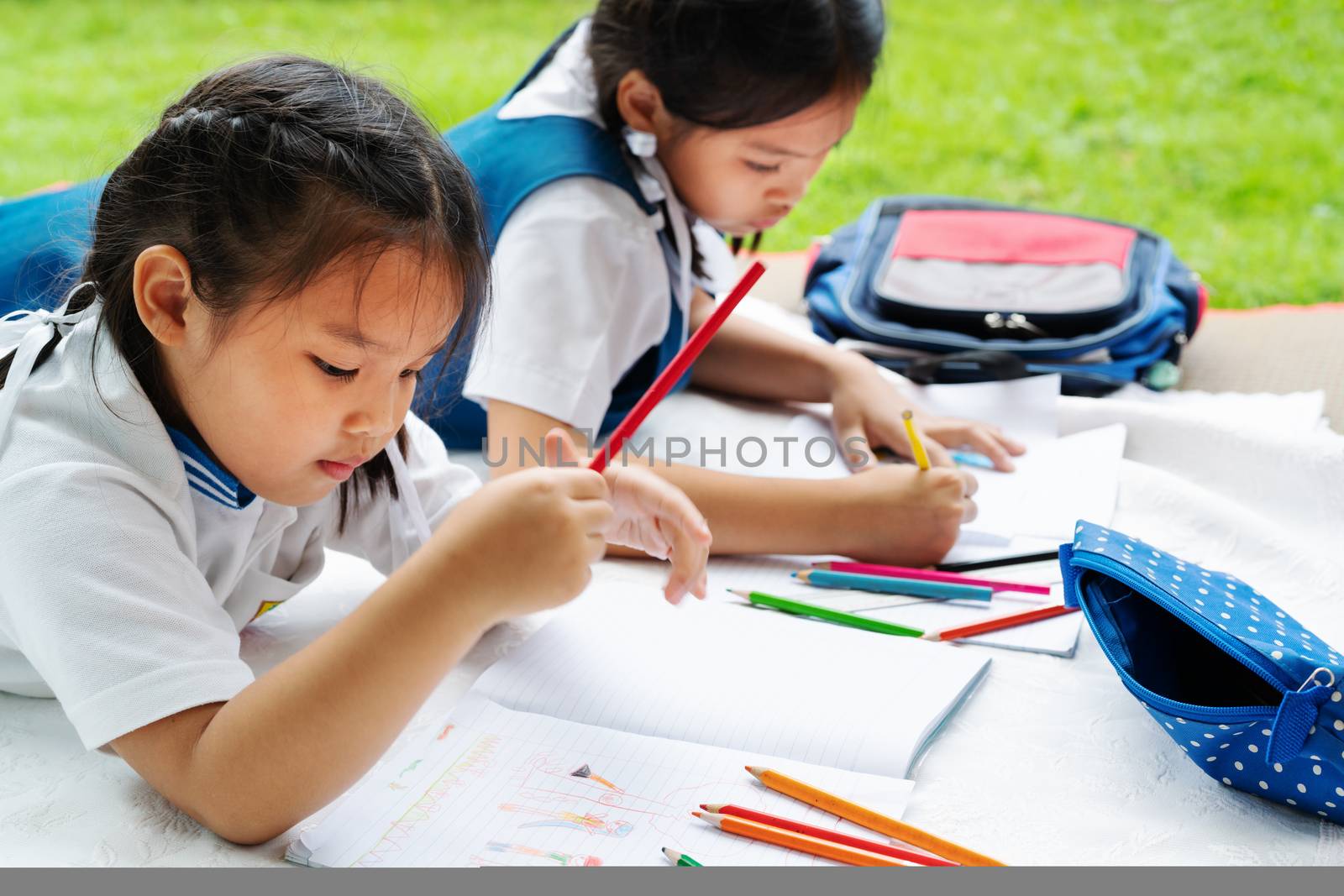 two sister girl writes to writing-books. The decision of lessons. girl lay down drawing the picture