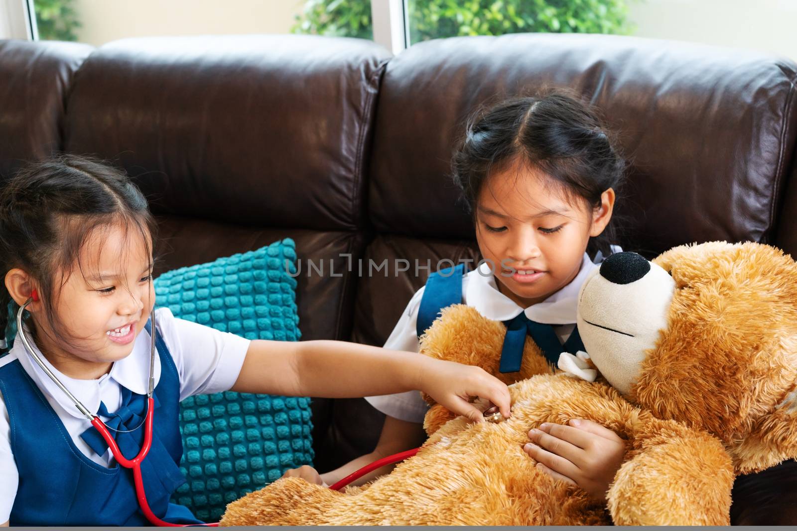 two little girl are smiling and playing doctor with stethoscope. by psodaz