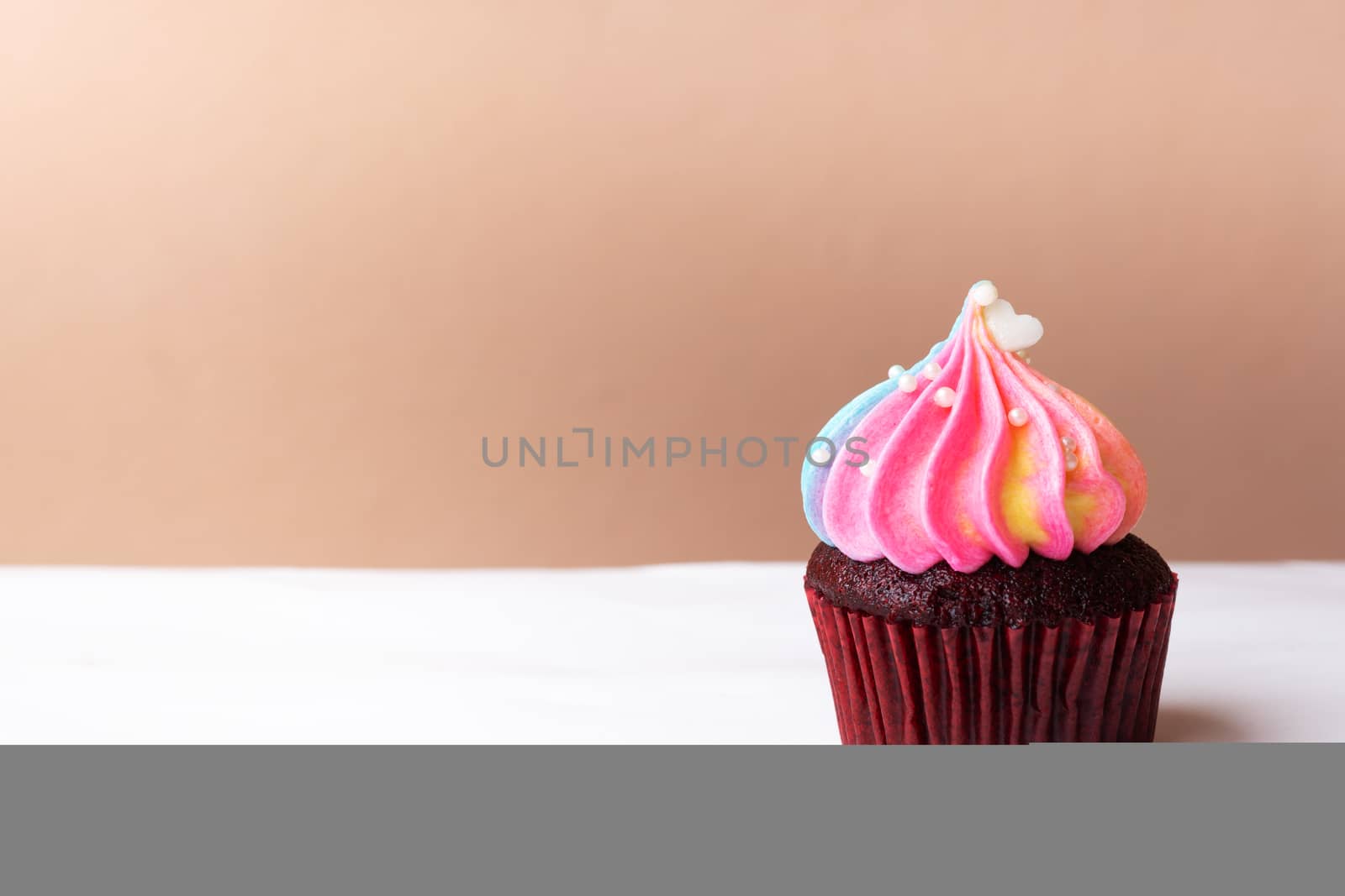 Cute little white heart on rainbow cream cupcake, sweet dessert concept