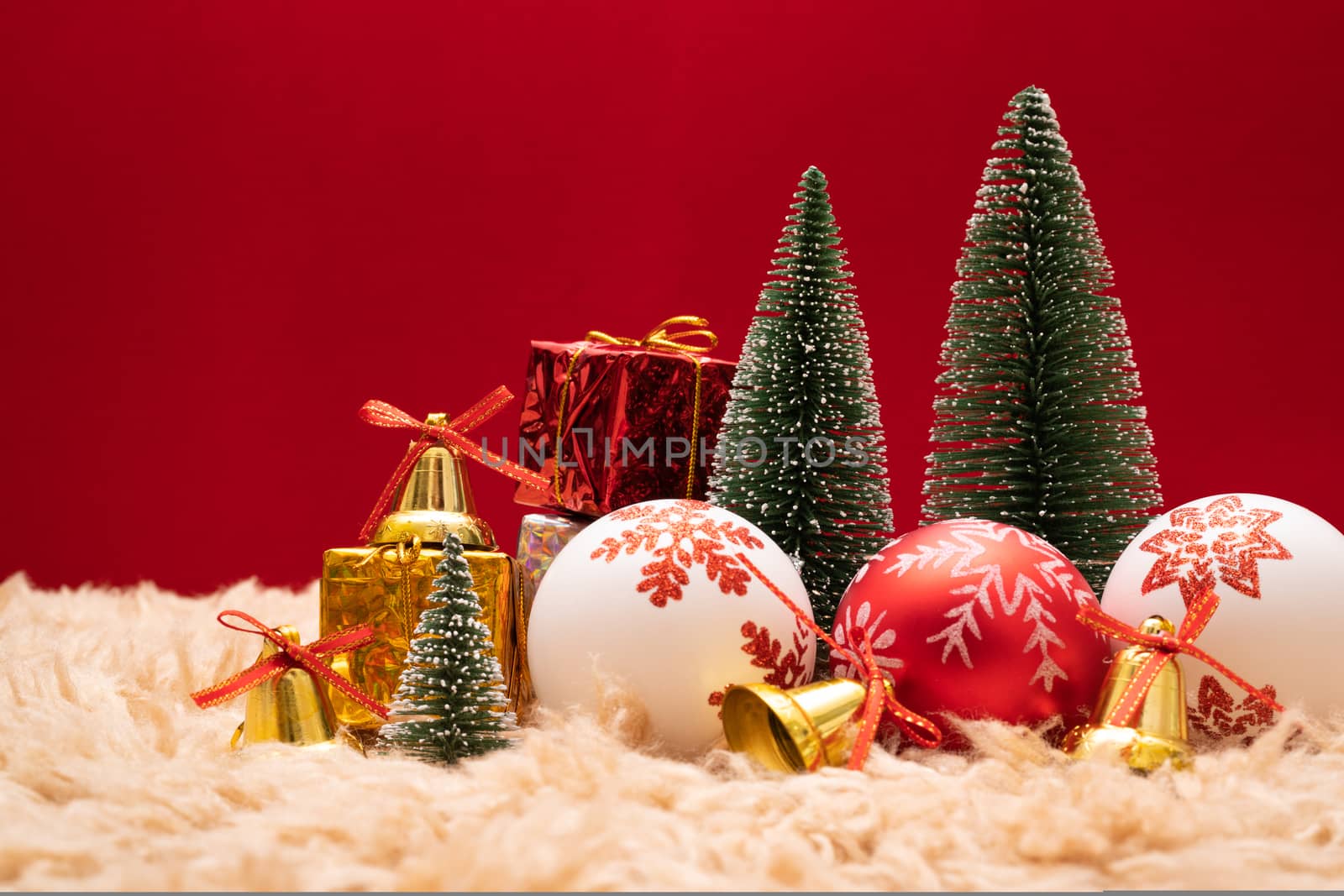 Christmas background concept. Christmas gift box and tree with golden bells, pine cones, red and white ball on red background
