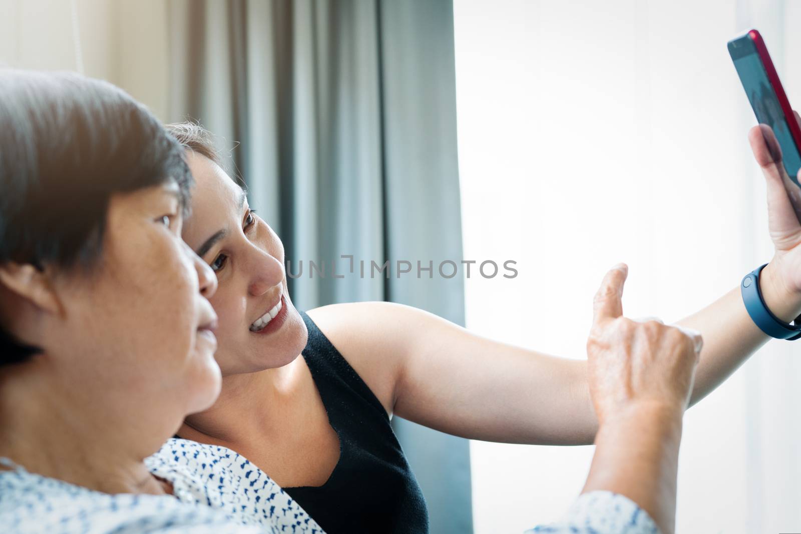 daughter and her mother making a selfie using smart phone and smiling