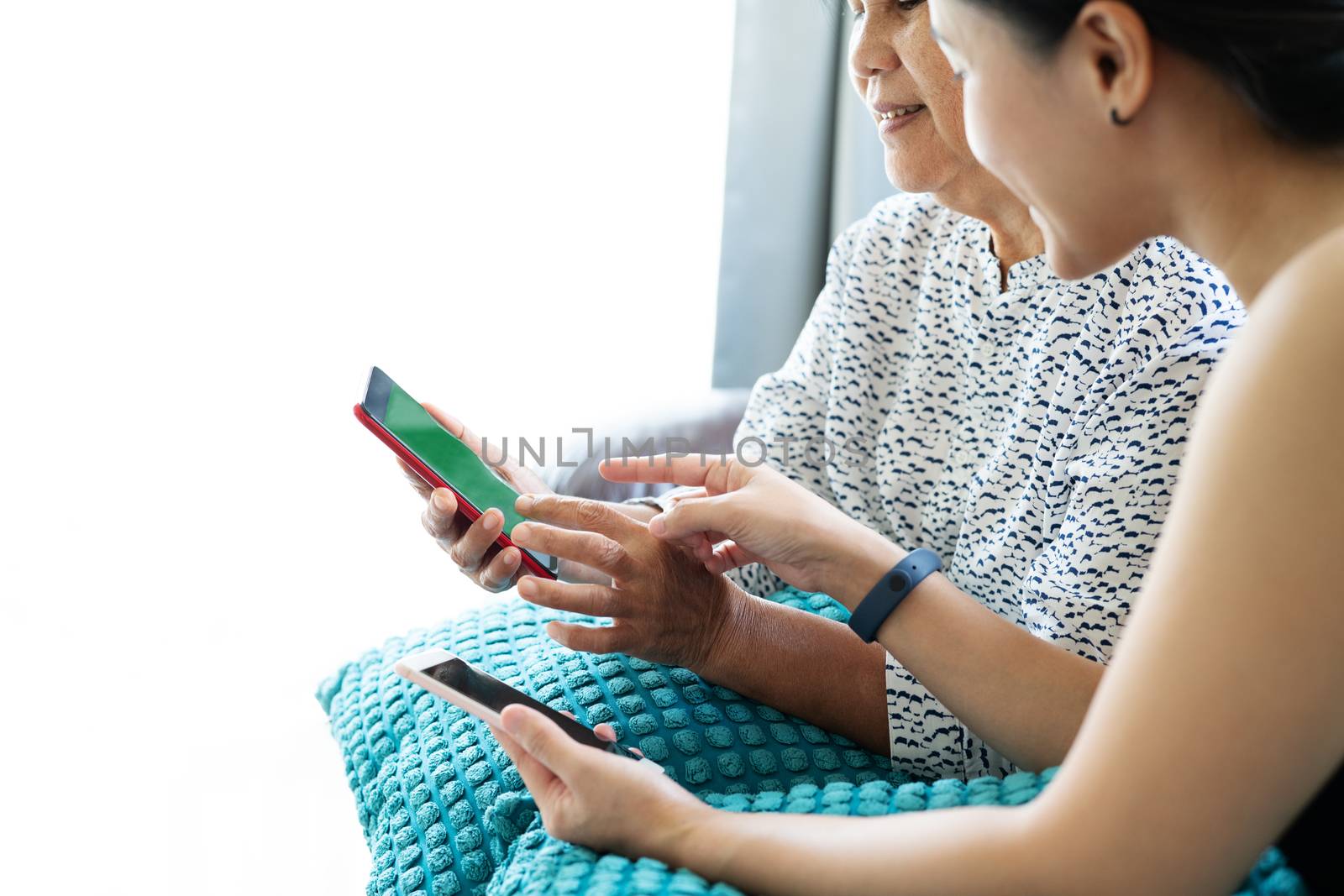 Adult woman and daughter using smartphone with blank screen. Woman pointing on mobile phone display