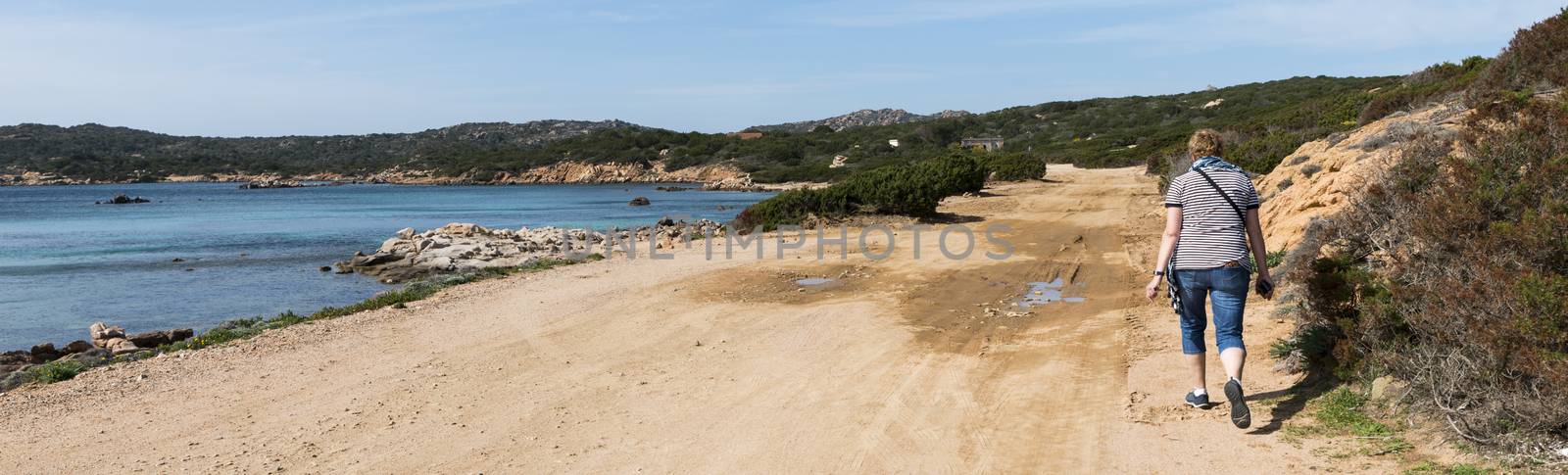 Caprera,Italy,07-april-2018:Adult womand walking along the roads of Caprera island, this island belongs to the maddalena archipel and you can reach it by bridge from maddalena