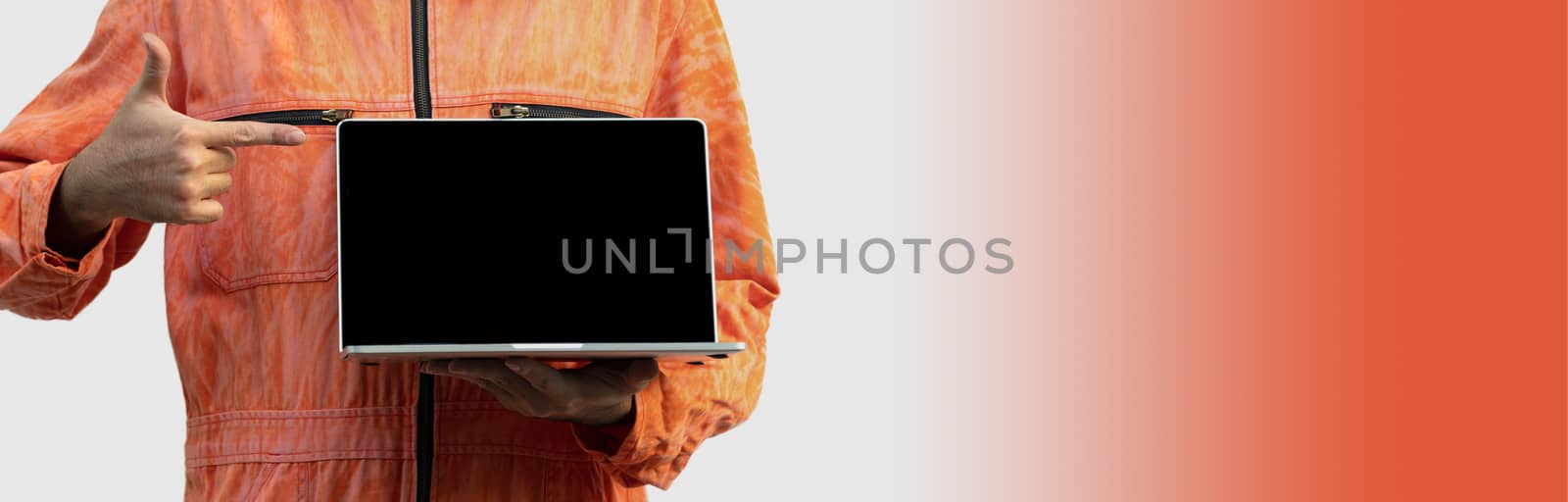 The chief mechanic in an orange uniform holding blank screen laptop by chadchai_k