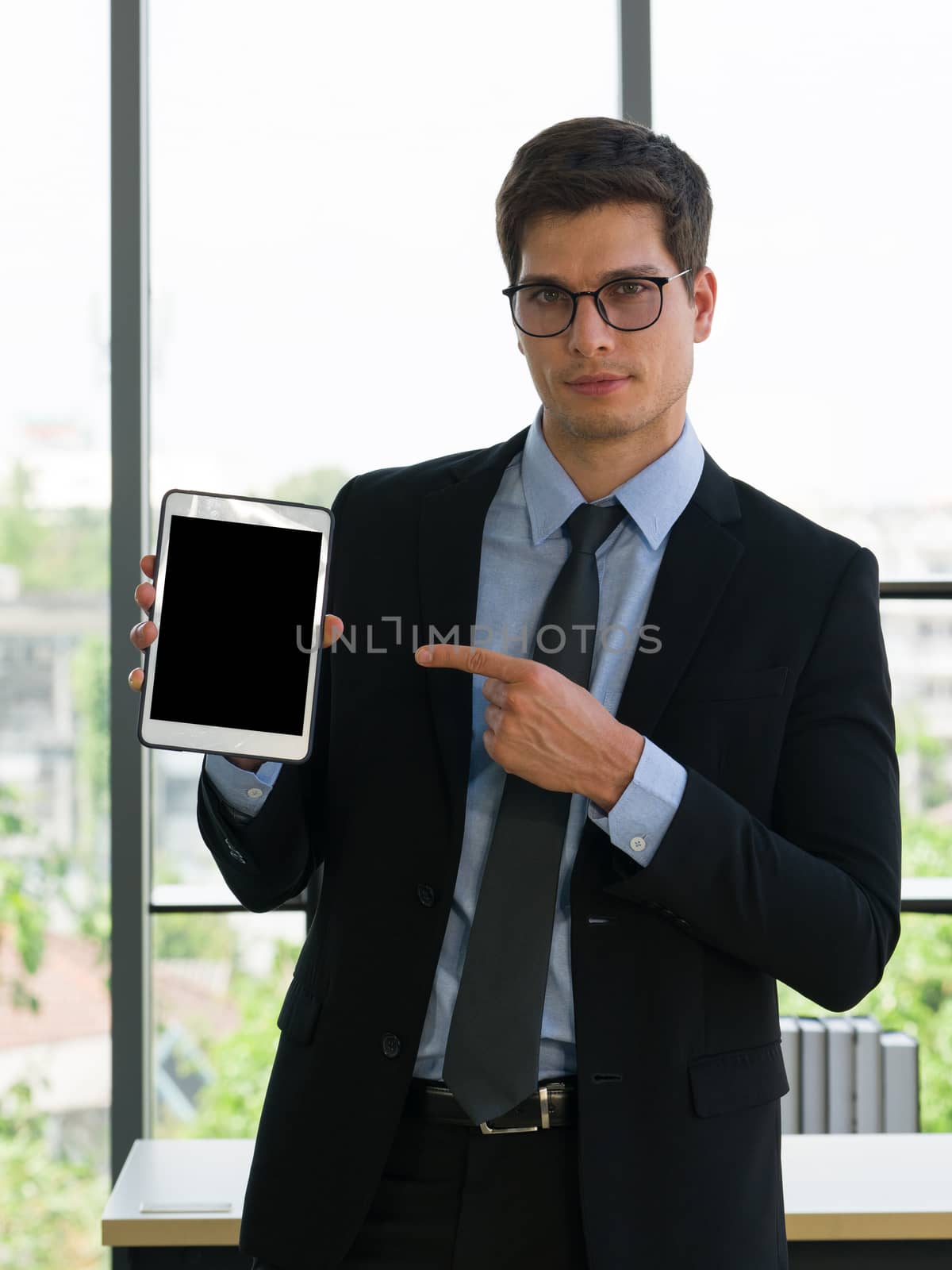 Business people in suits and ties pointing his finger at a blank screen tablet computer. Morning work atmosphere In a modern office.