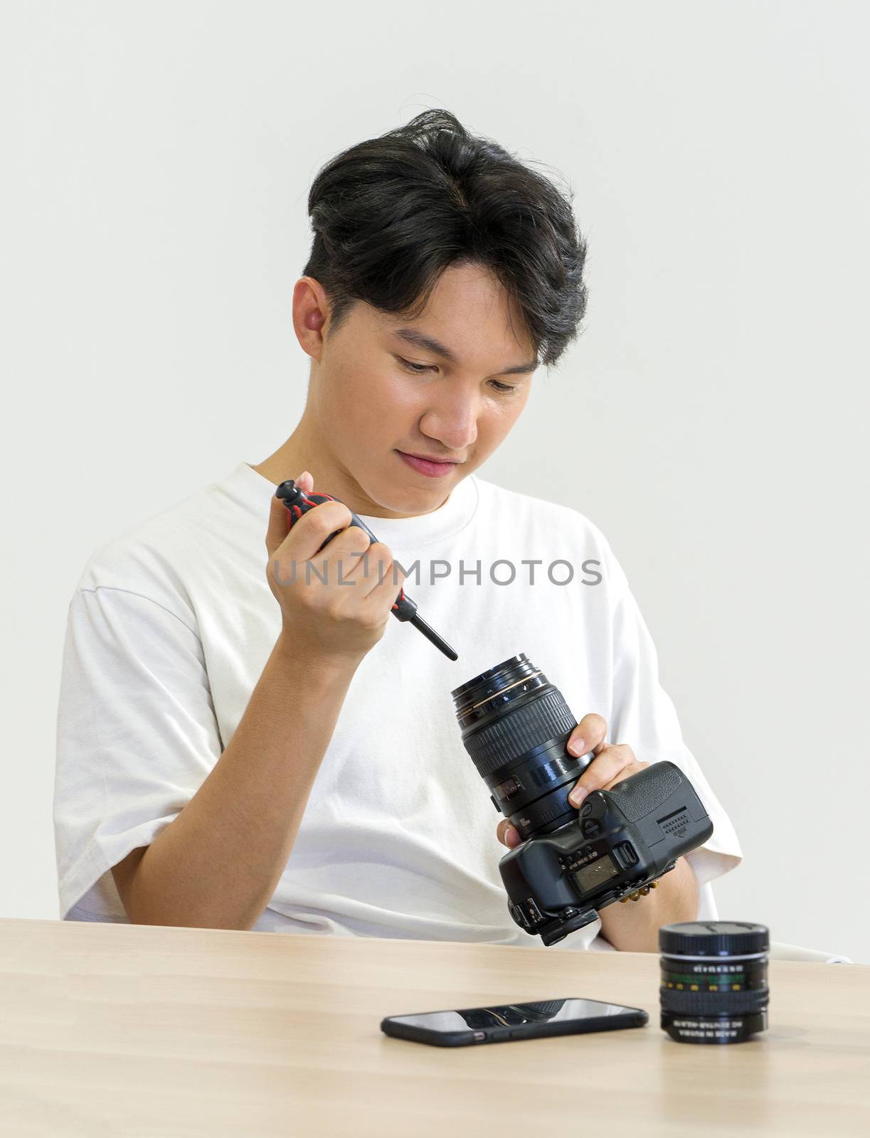 An Asian photographer is cleaning the camera and lens with a air blower camera cleaning for shooting fashion models in the studio.
