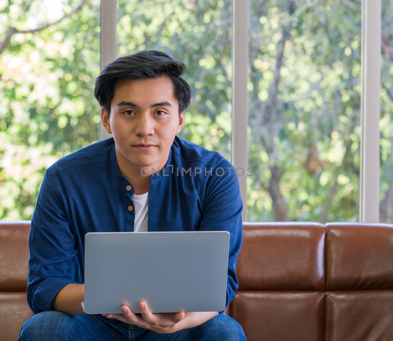 Young asian man wore comfortable clothes use laptop computer to search for jobs. by chadchai_k