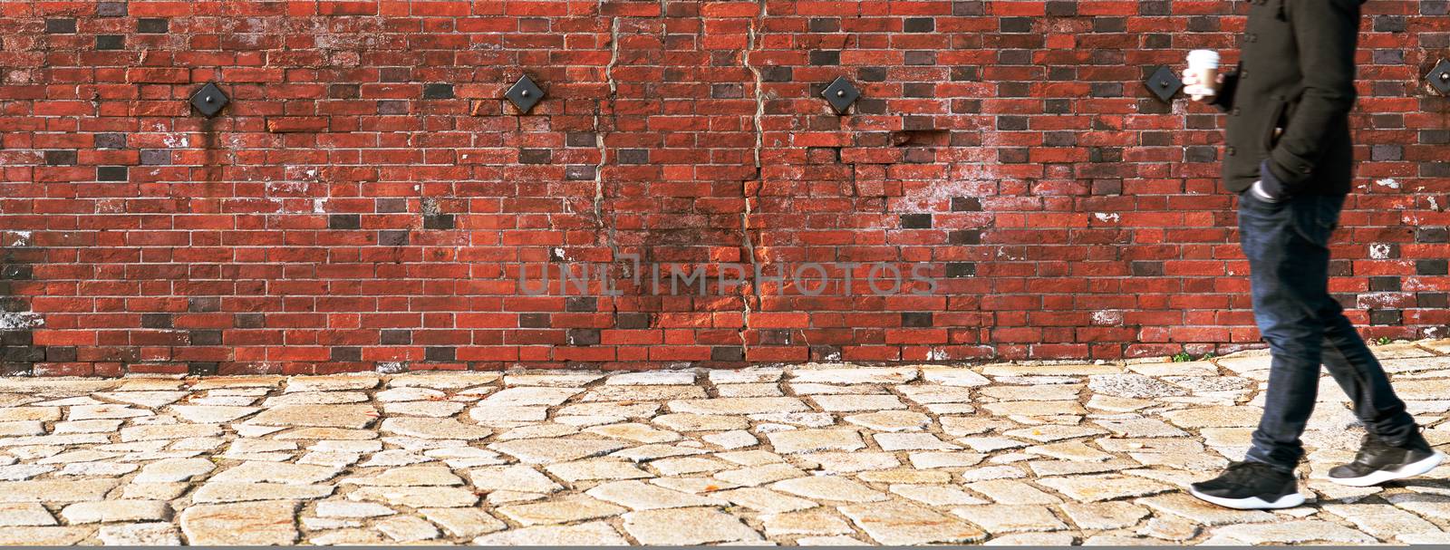 blurred man walking through a old weathered brick wall hold coffee cup