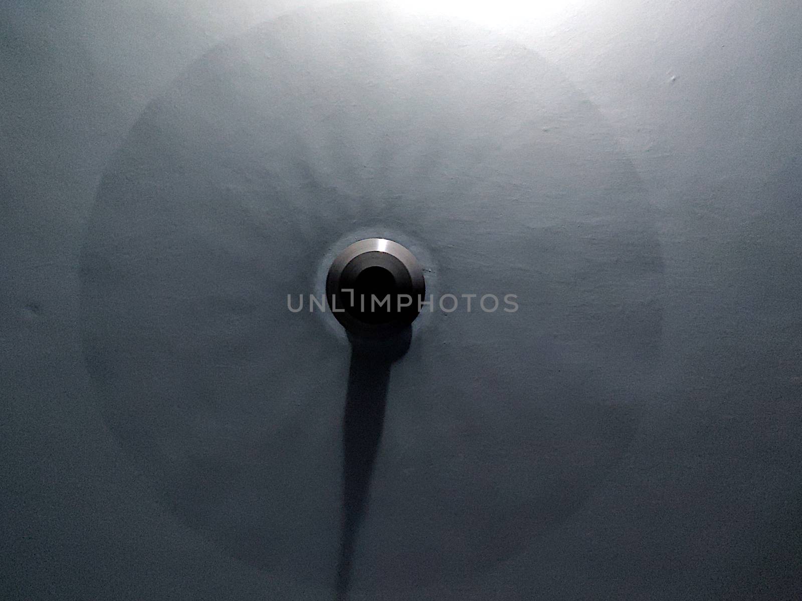 A ceiling fan in blue light with blades whirring