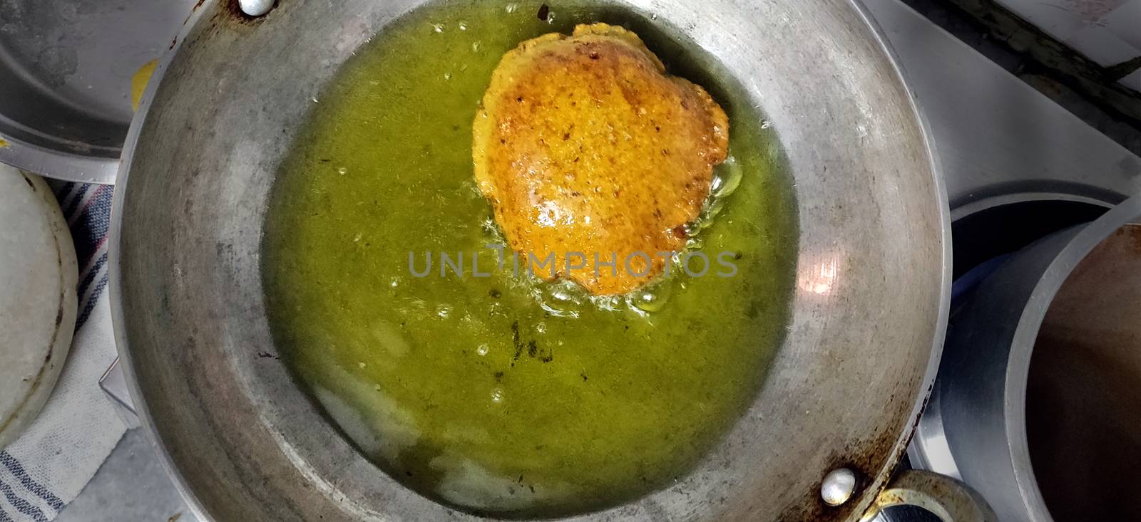 Deep fried Indian bread called Puri in a cooking pan with vegetable oil