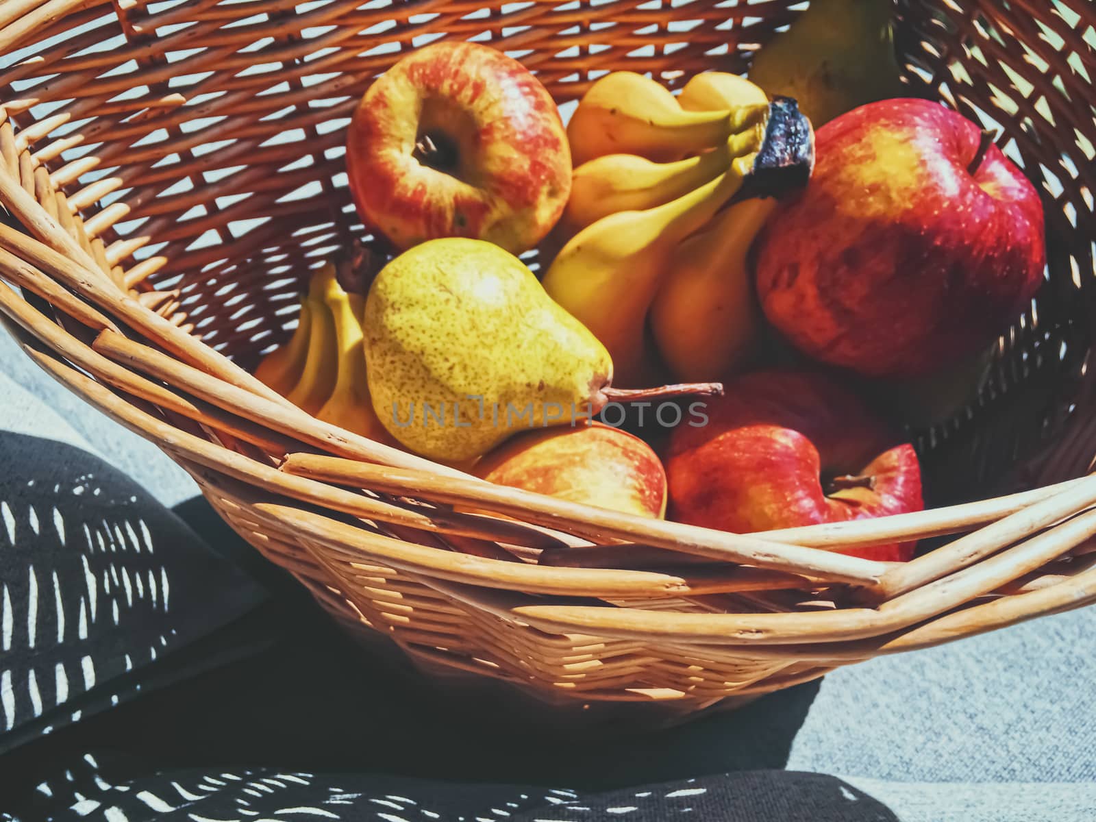 Organic apples, pears and bananas on rustic in a wicker basket, fruits farming and agriculture