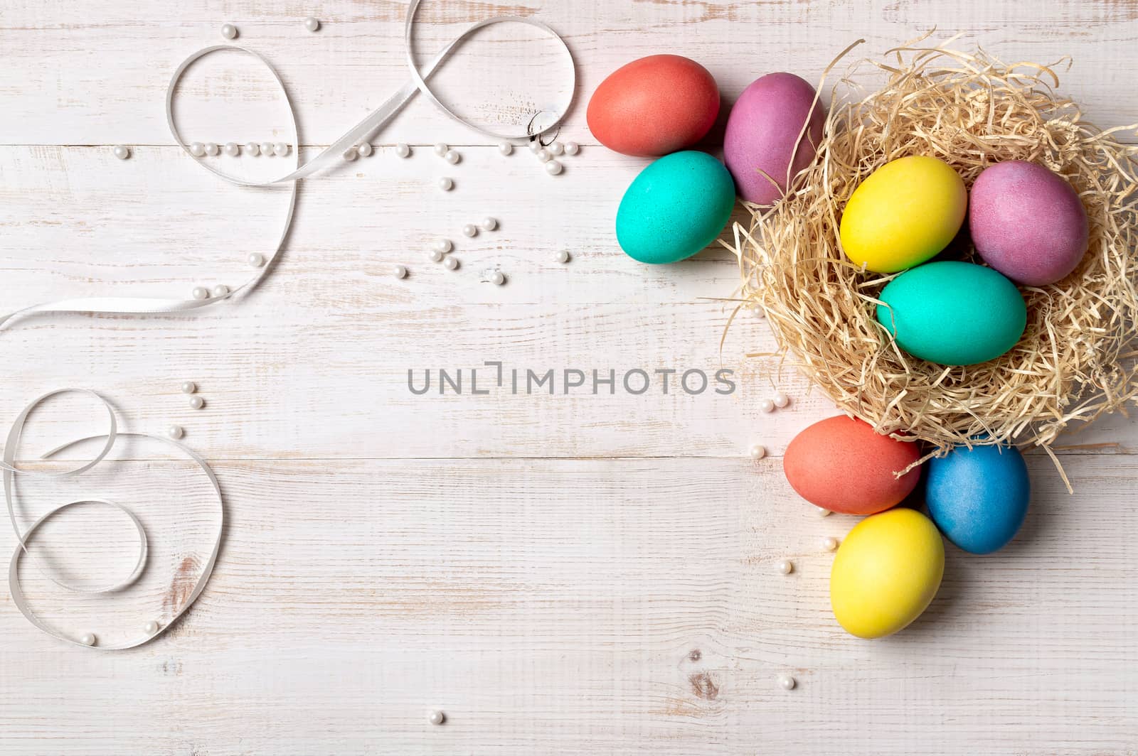 Easter concept. Colorful eggs on white wooden background with copy space for text or design. Top down view or flat lay