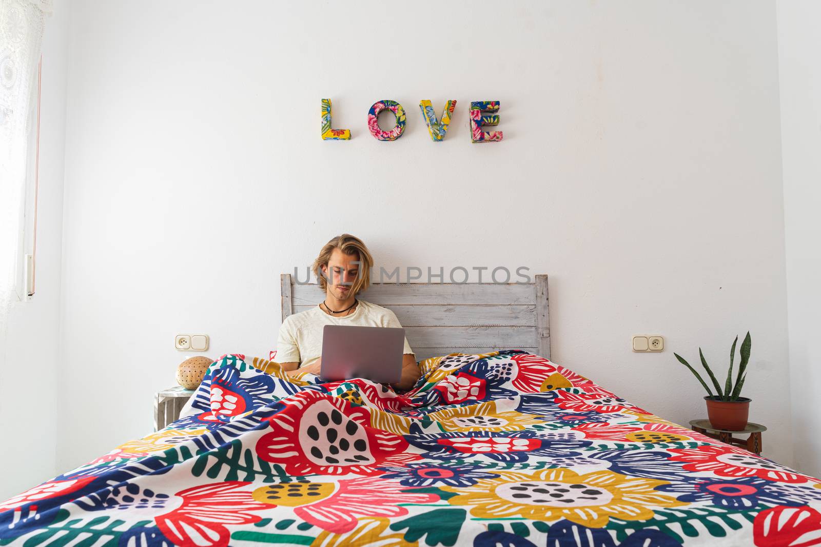 Young man talking on the laptop computer in bed by Dumblinfilms