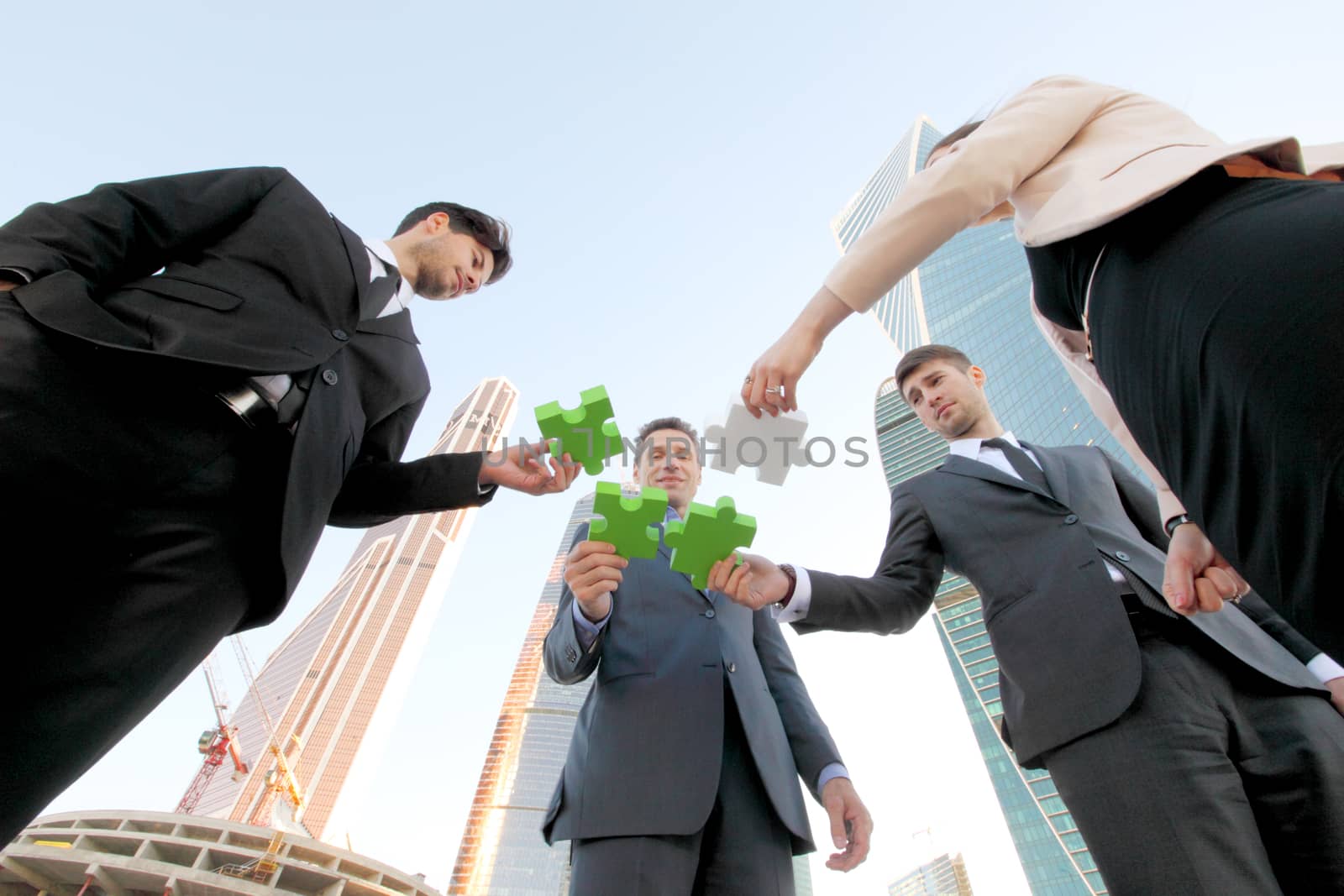 Closeup of business people wanting to put four pieces of puzzle together outdoors, Team work concept