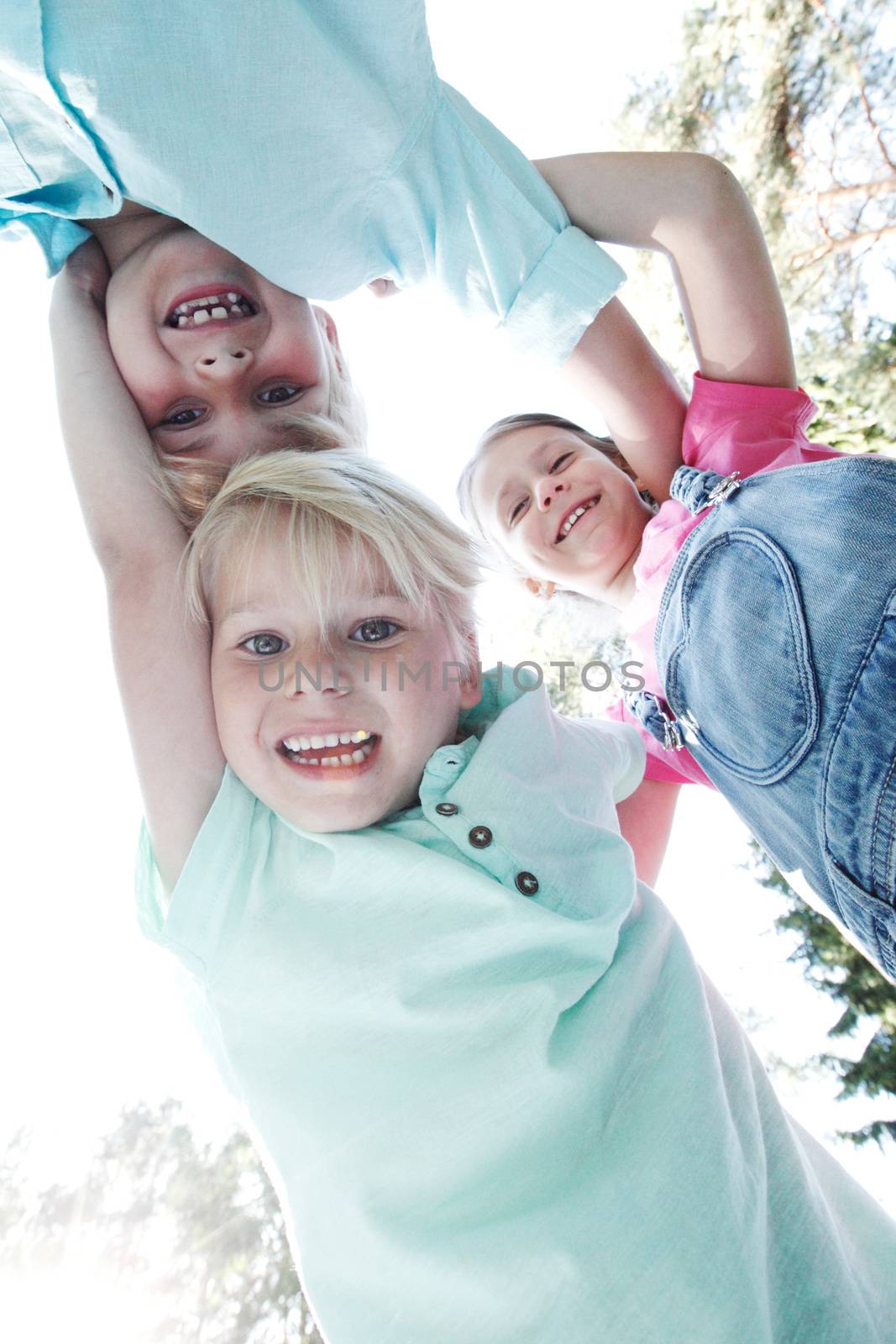 Group of three children friends outdoors looking down and smiling