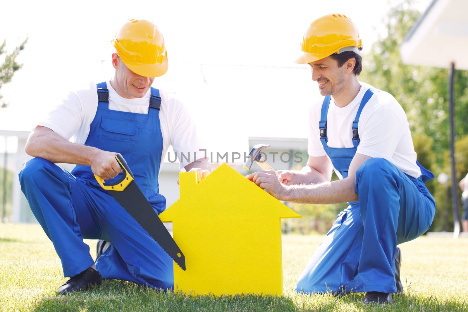 Workers with yellow house model building construction concept
