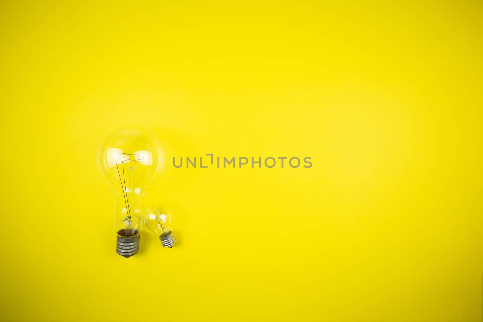 Two bulbs - large and small. Yellow background, tehnology
