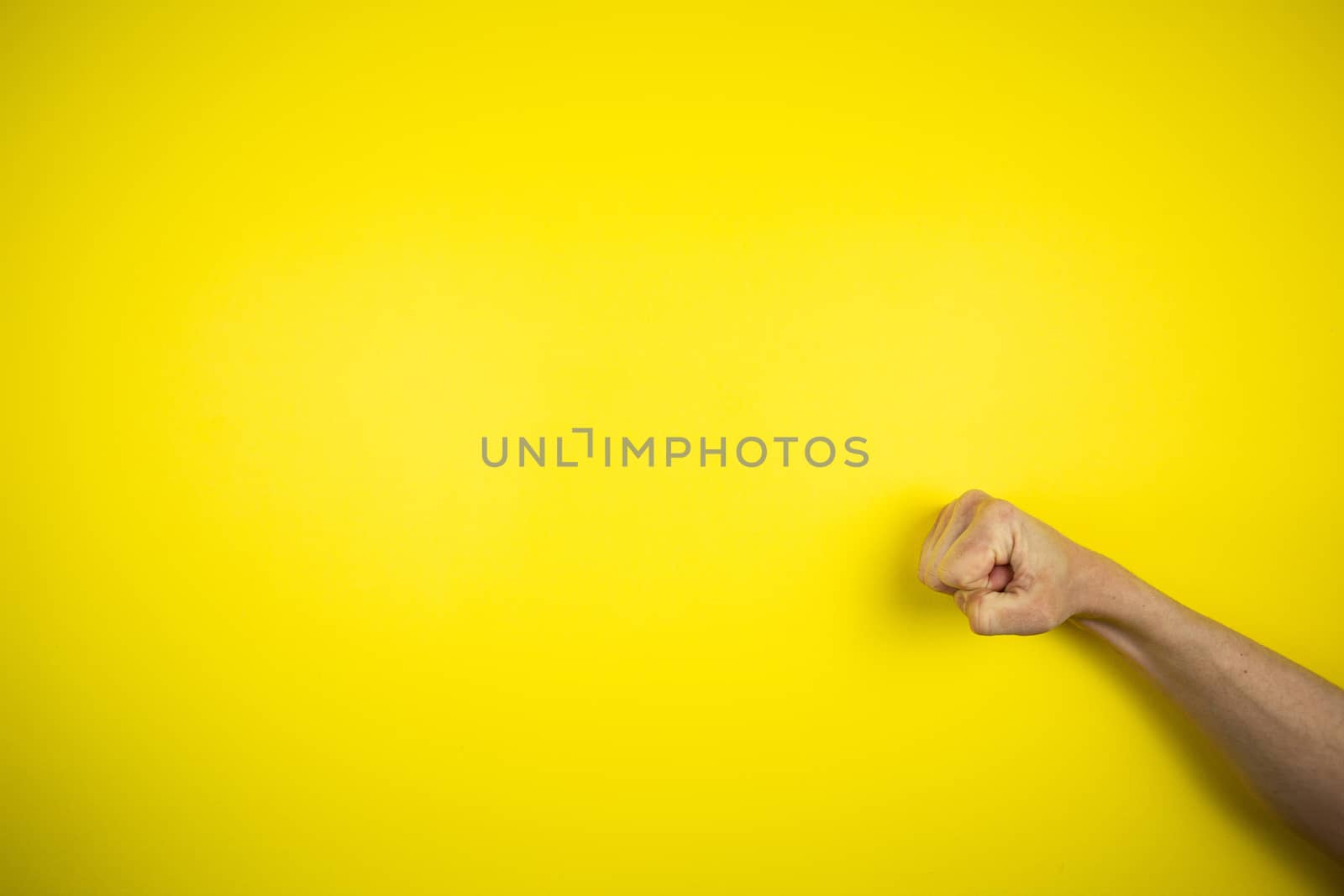 Punch, knock hand gesture on a yellow background by Grinchenkophoto