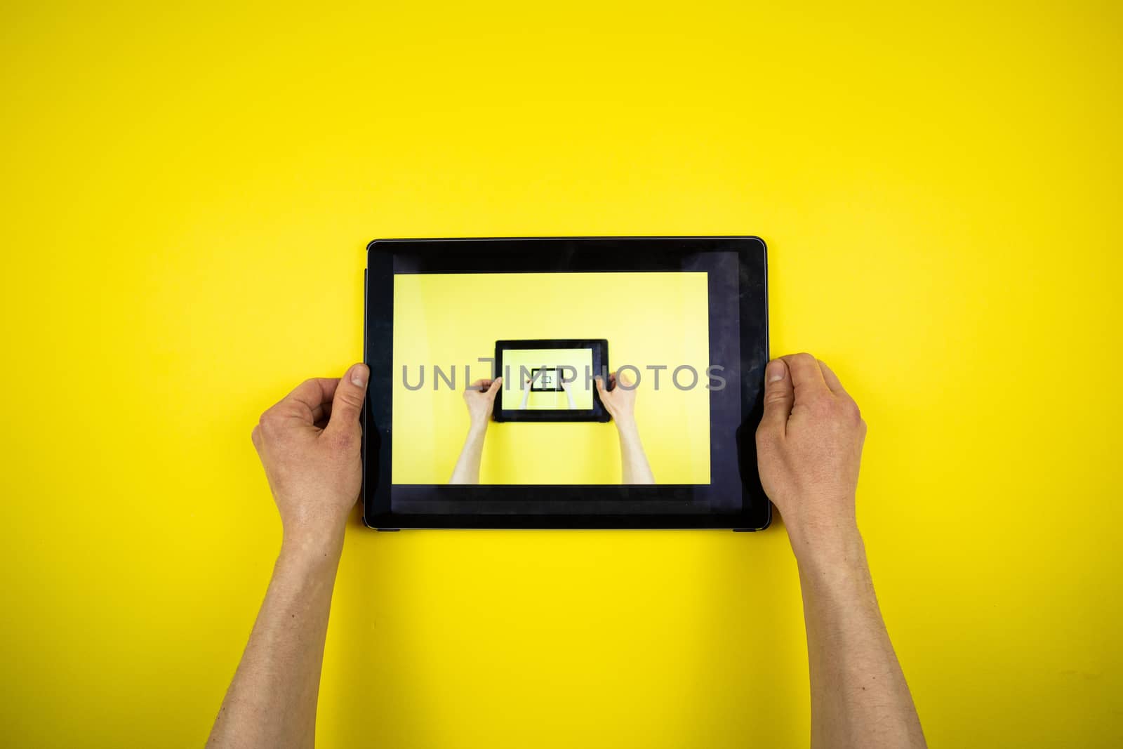 Tablet in hands on a yellow background. Picture in Picture