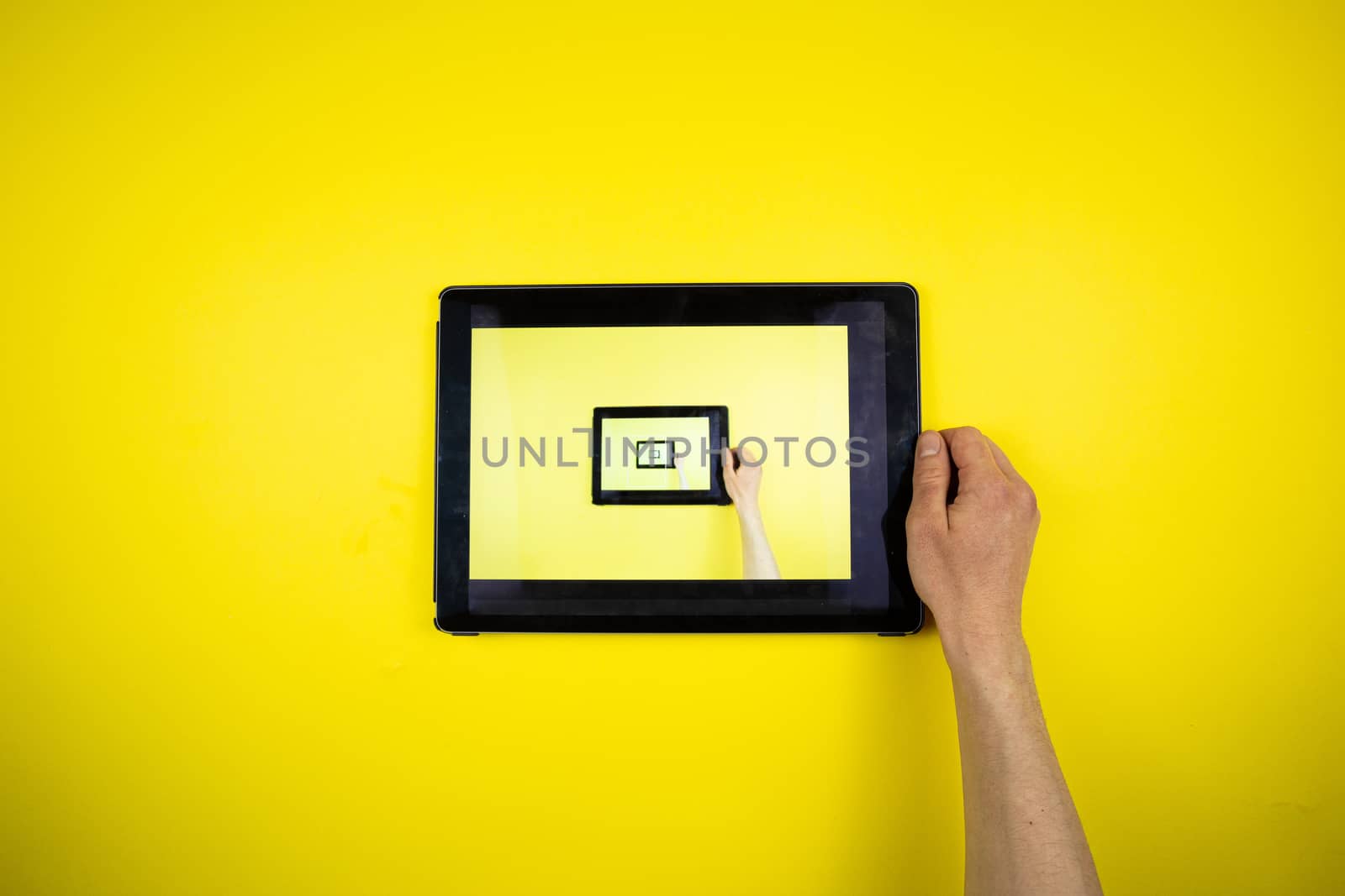 Tablet in hands on a yellow background. Picture in Picture