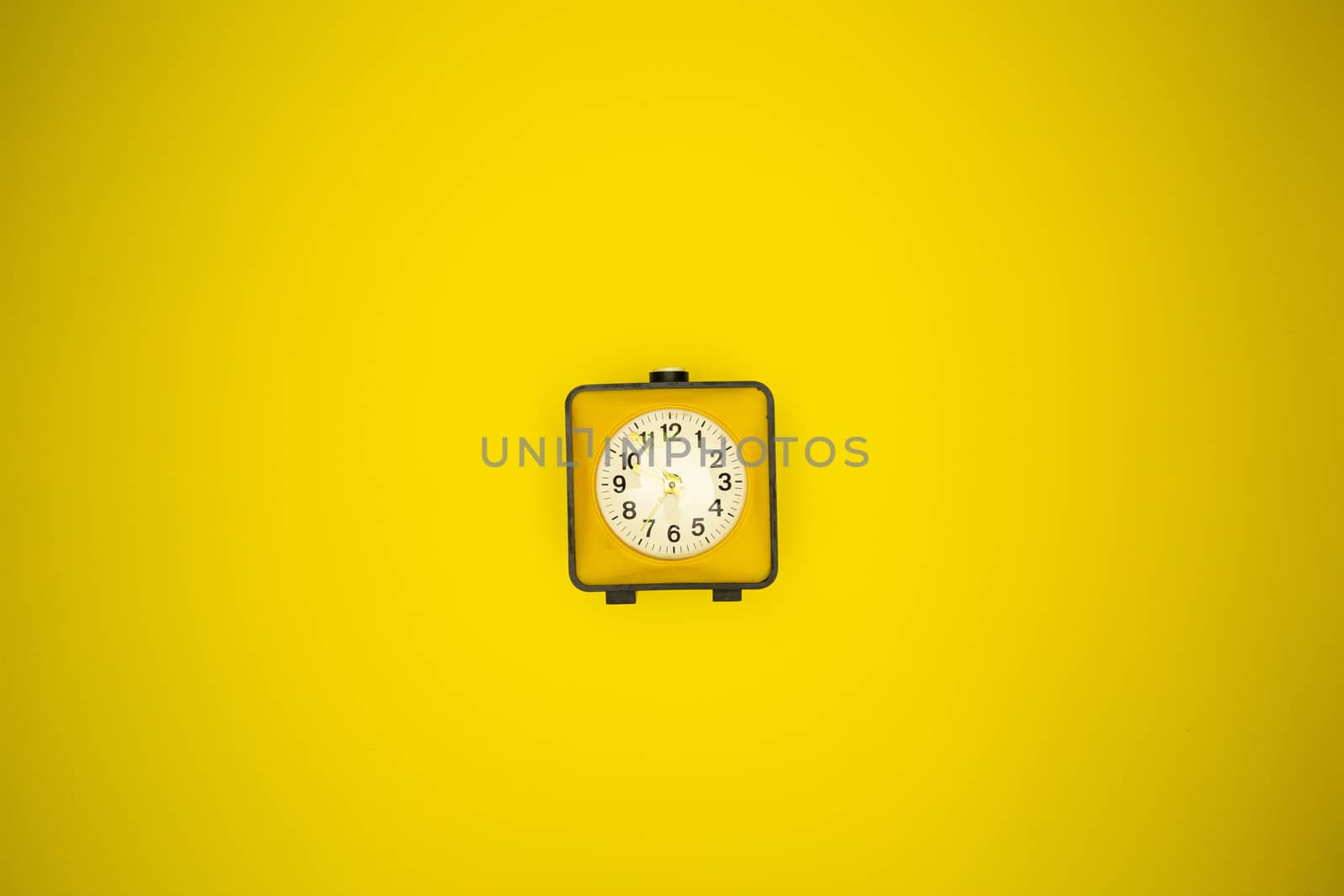 Yellow alarm clock on a yellow background