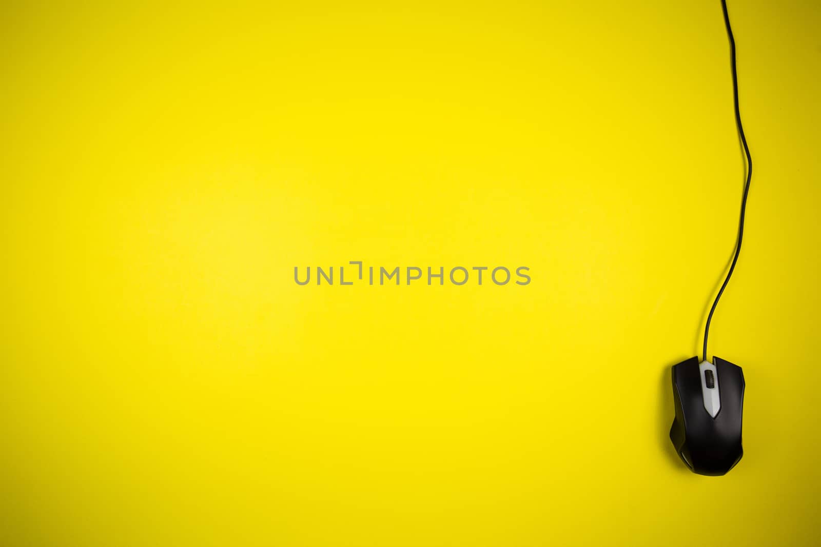 Computer yellow mouse with a long wire on a yellow background