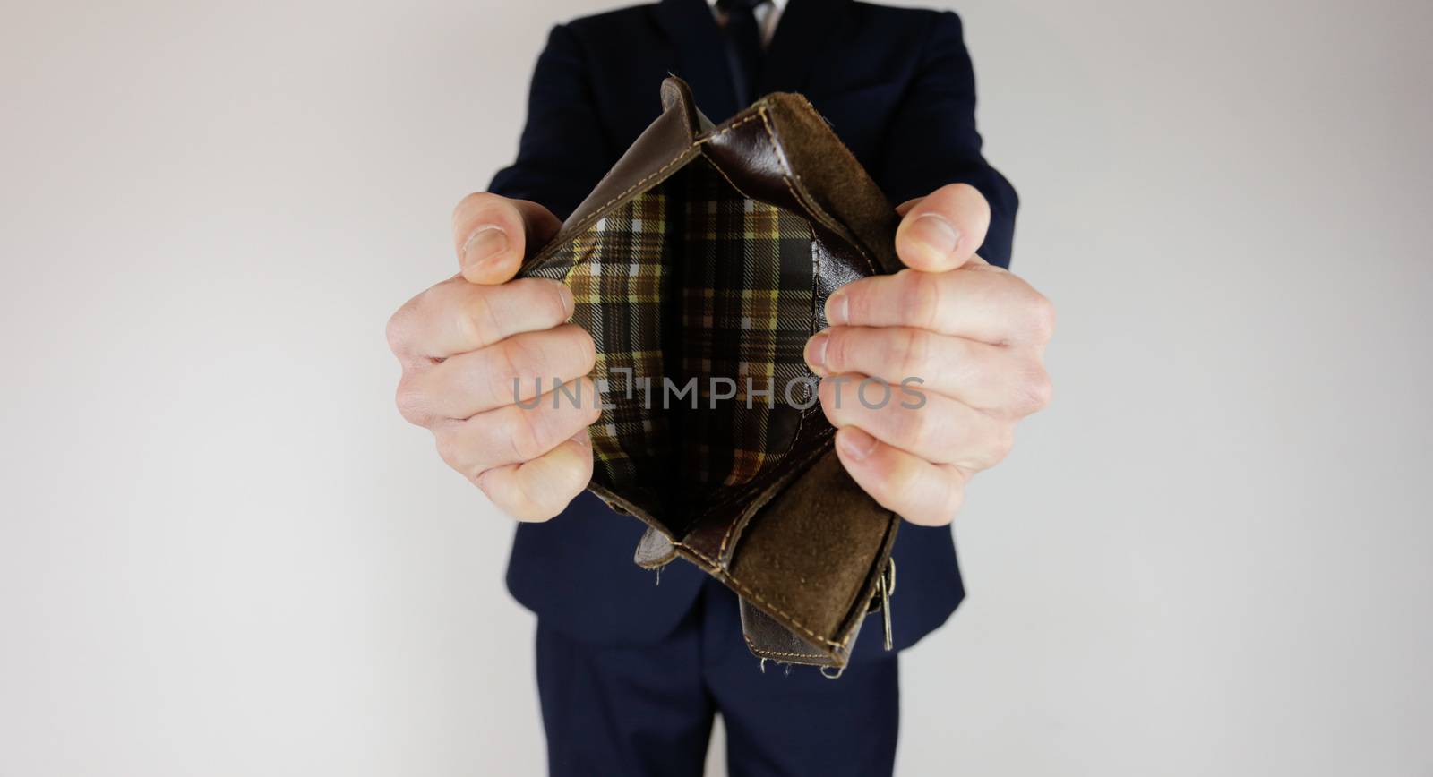 A man in a business suit holds in his hands an empty wallet without money. Financial crisis. Bankruptcy in business. The employer is disappointed.