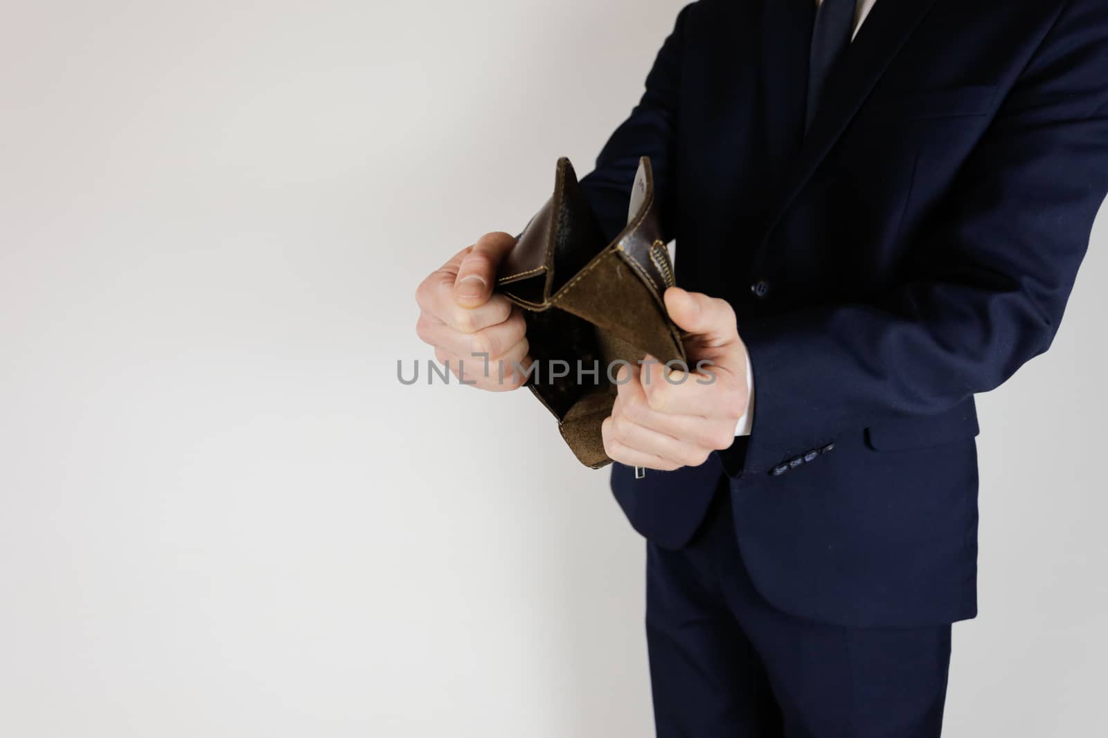 A man in a business suit holds in his hands an empty wallet without money. Financial crisis. Bankruptcy in business. The employer is disappointed.