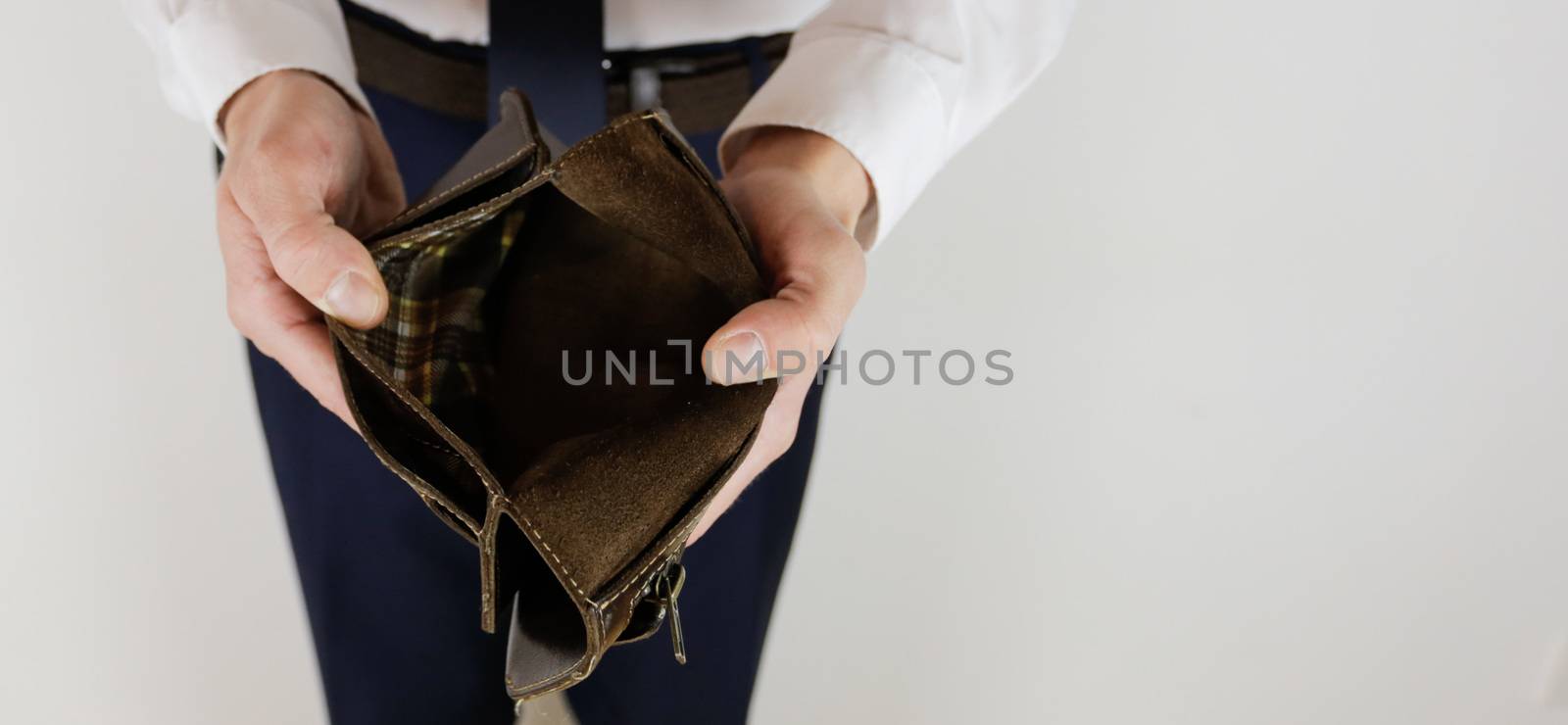 A man in a business suit holds in his hands an empty wallet without money. Financial crisis. Bankruptcy in business. The employer is disappointed.