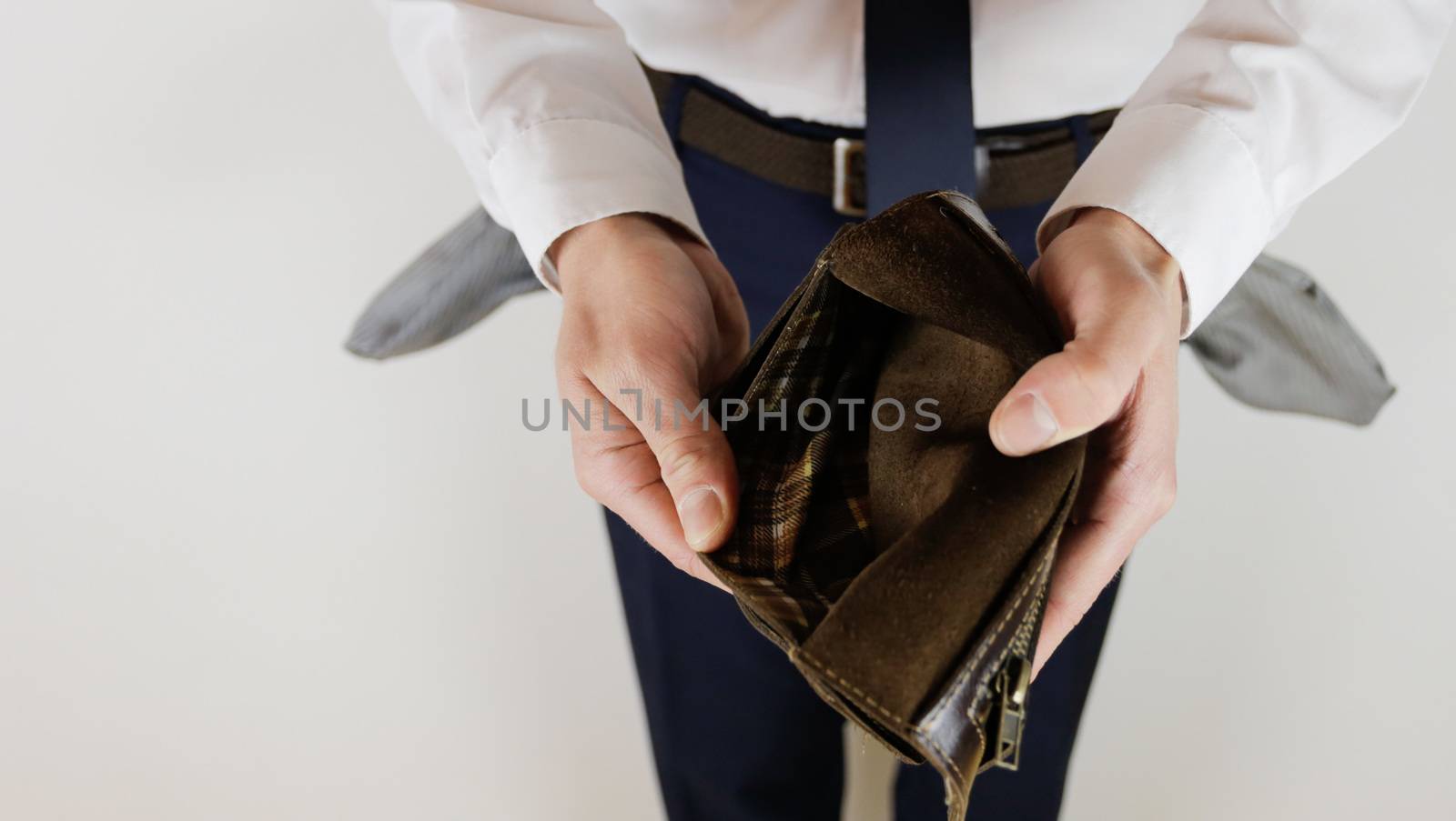 A man in a business suit holds in his hands an empty wallet without money. Financial crisis. Bankruptcy in business. The employer is disappointed.