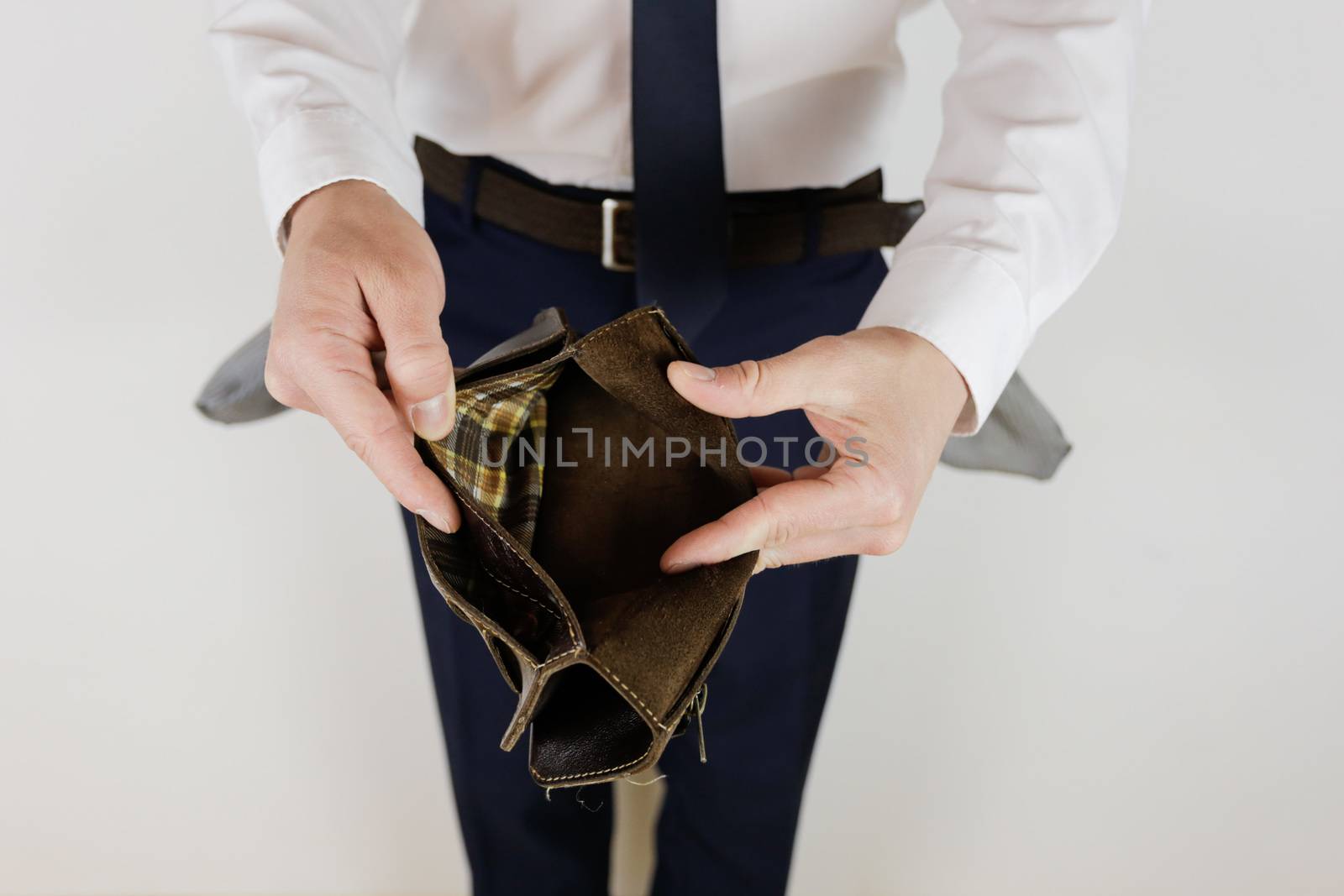 A man in a business suit holds in his hands an empty wallet without money. Financial crisis. Bankruptcy in business. The employer is disappointed.